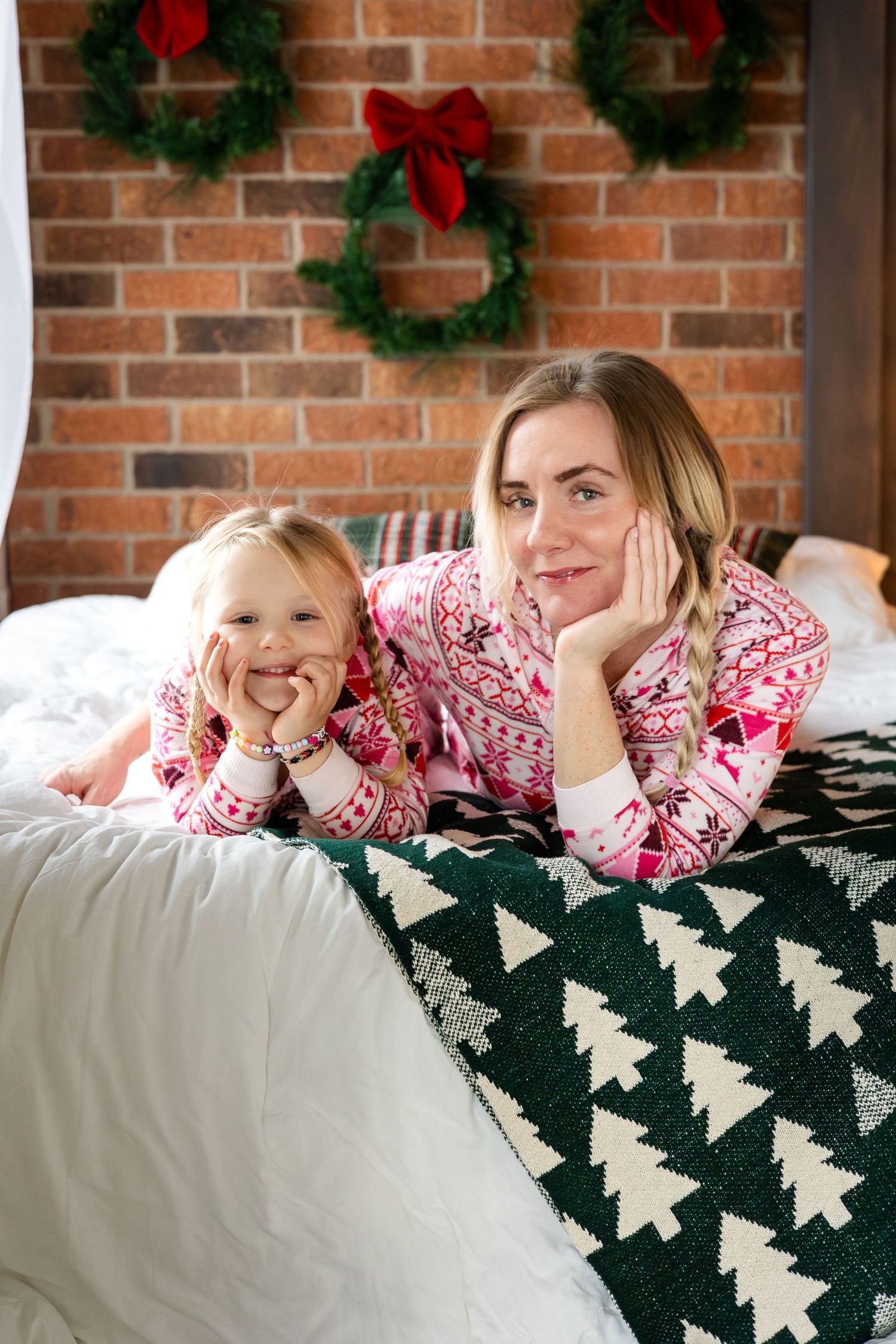 Festive setting with Christmas tree print blanket and brick wall decorated with wreaths.
