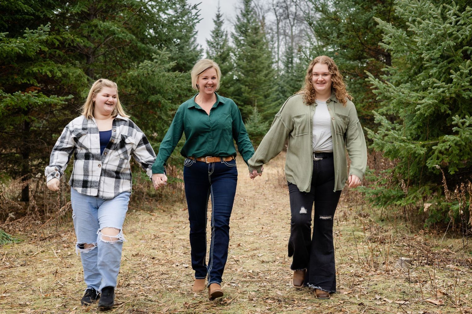 People walking together through a wooded area with evergreen trees and fallen leaves.