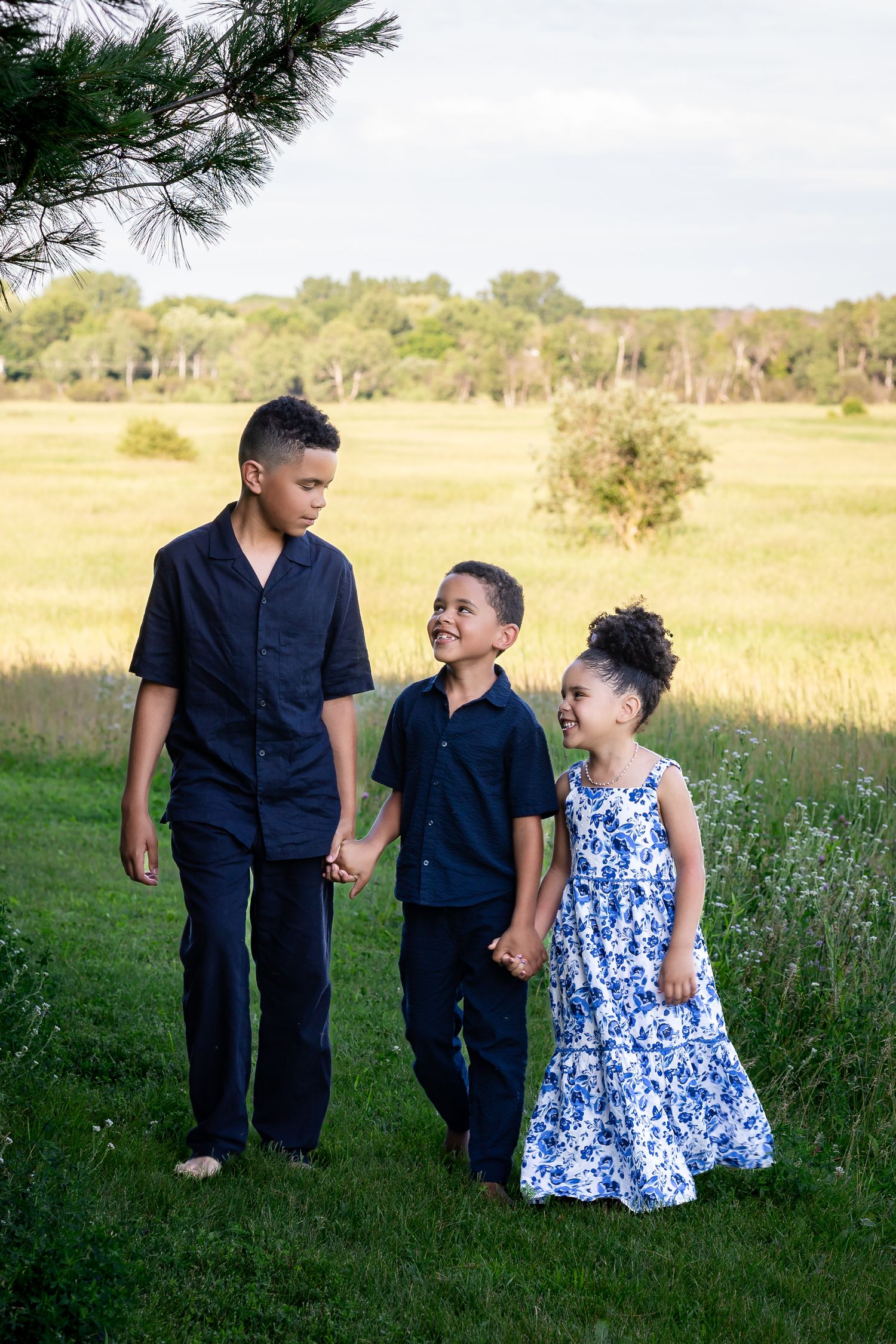 Family walking together through tall grass wearing coordinating navy and blue floral outfits.