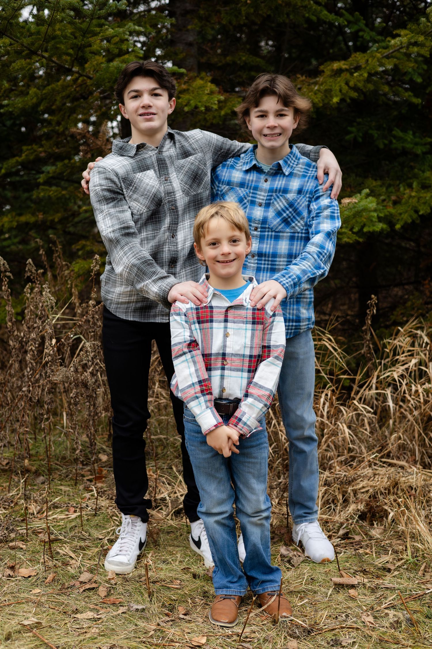 People in plaid shirts pose together for a casual outdoor portrait.