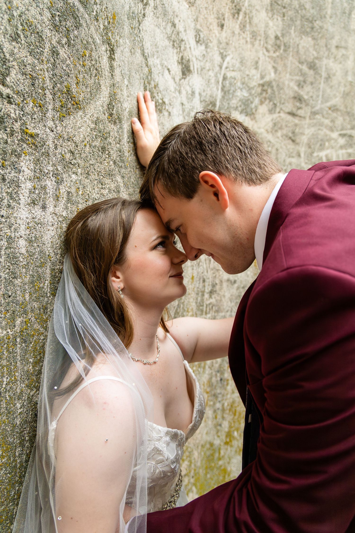 A romantic wedding couple shares intimate moments against a stone wall in a sequence of photos.