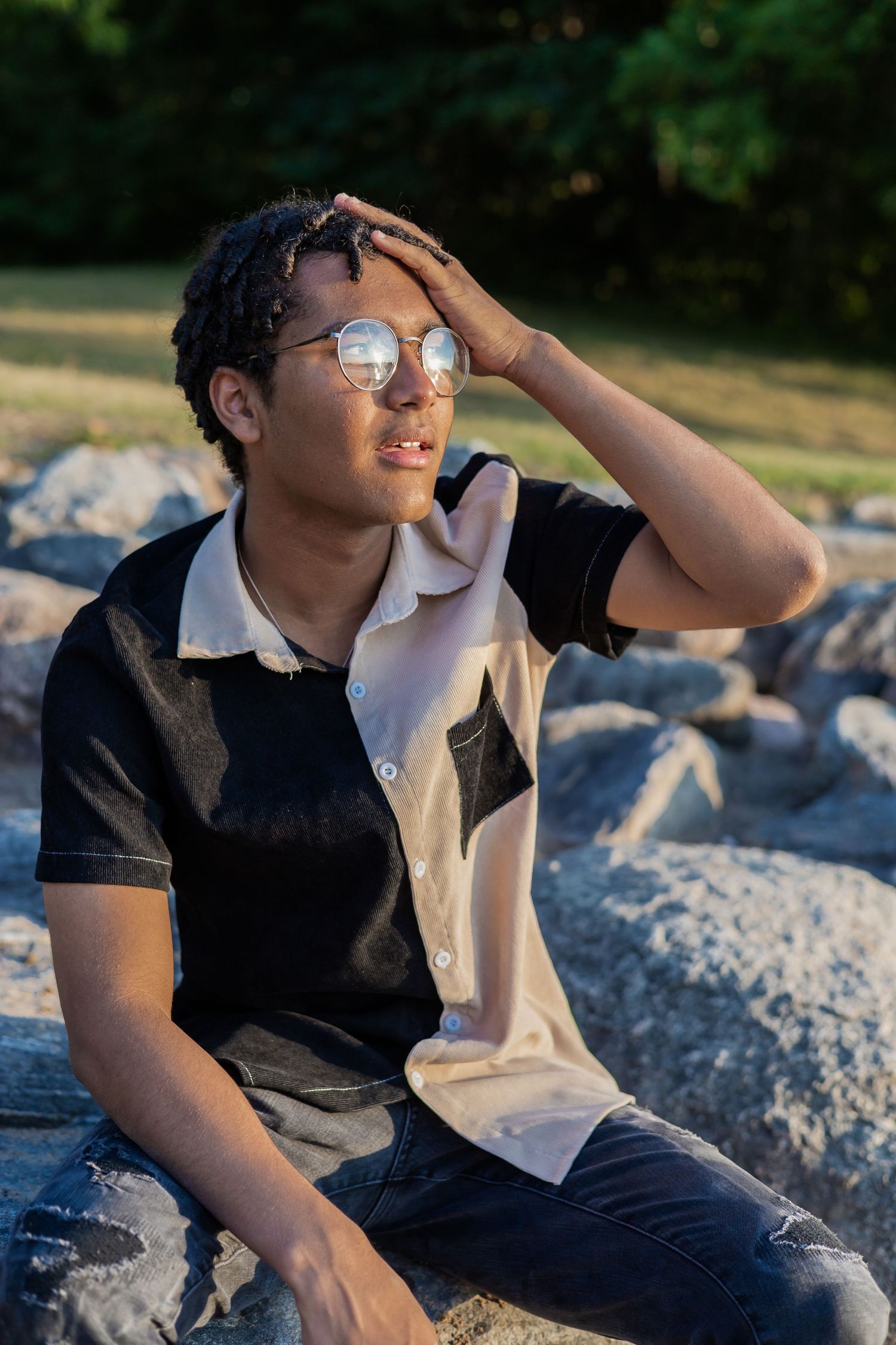 Person relaxing on rocky shore wearing black and white color block shirt.