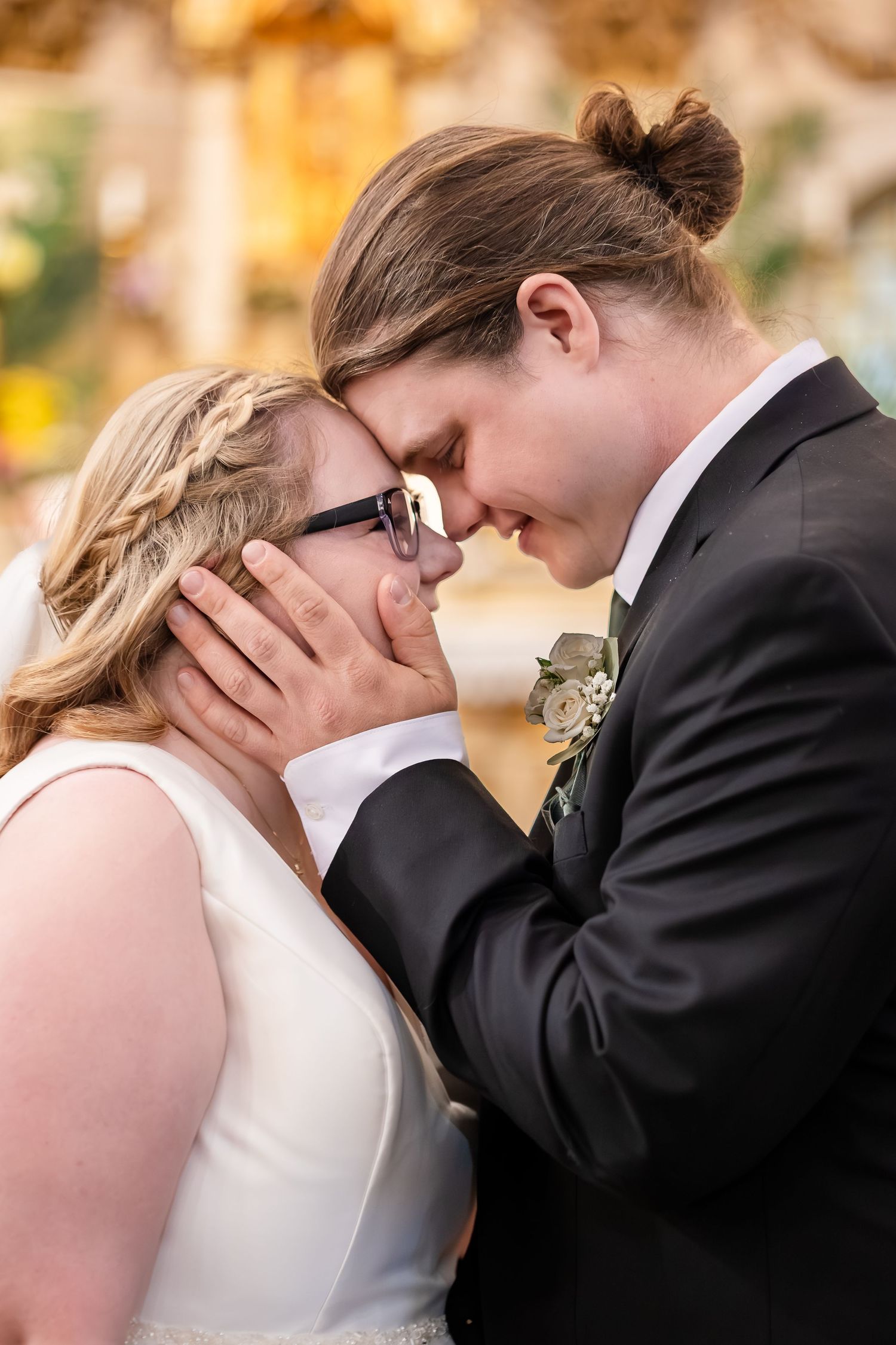 Bride and groom touch foreheads tenderly in an intimate wedding moment, with the groom cradling her face gently.
