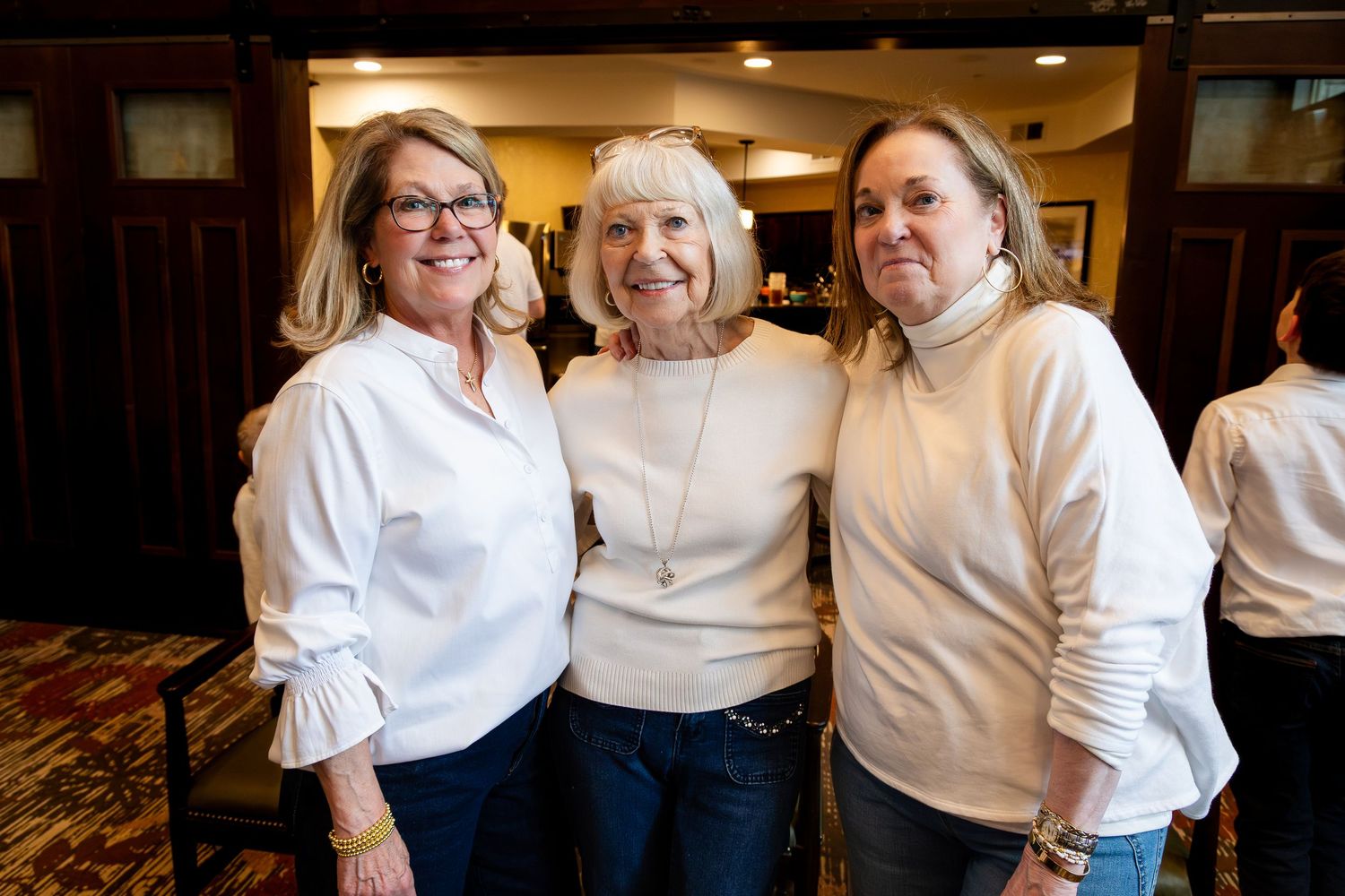 A family group wearing coordinated white tops and blue jeans poses together indoors.