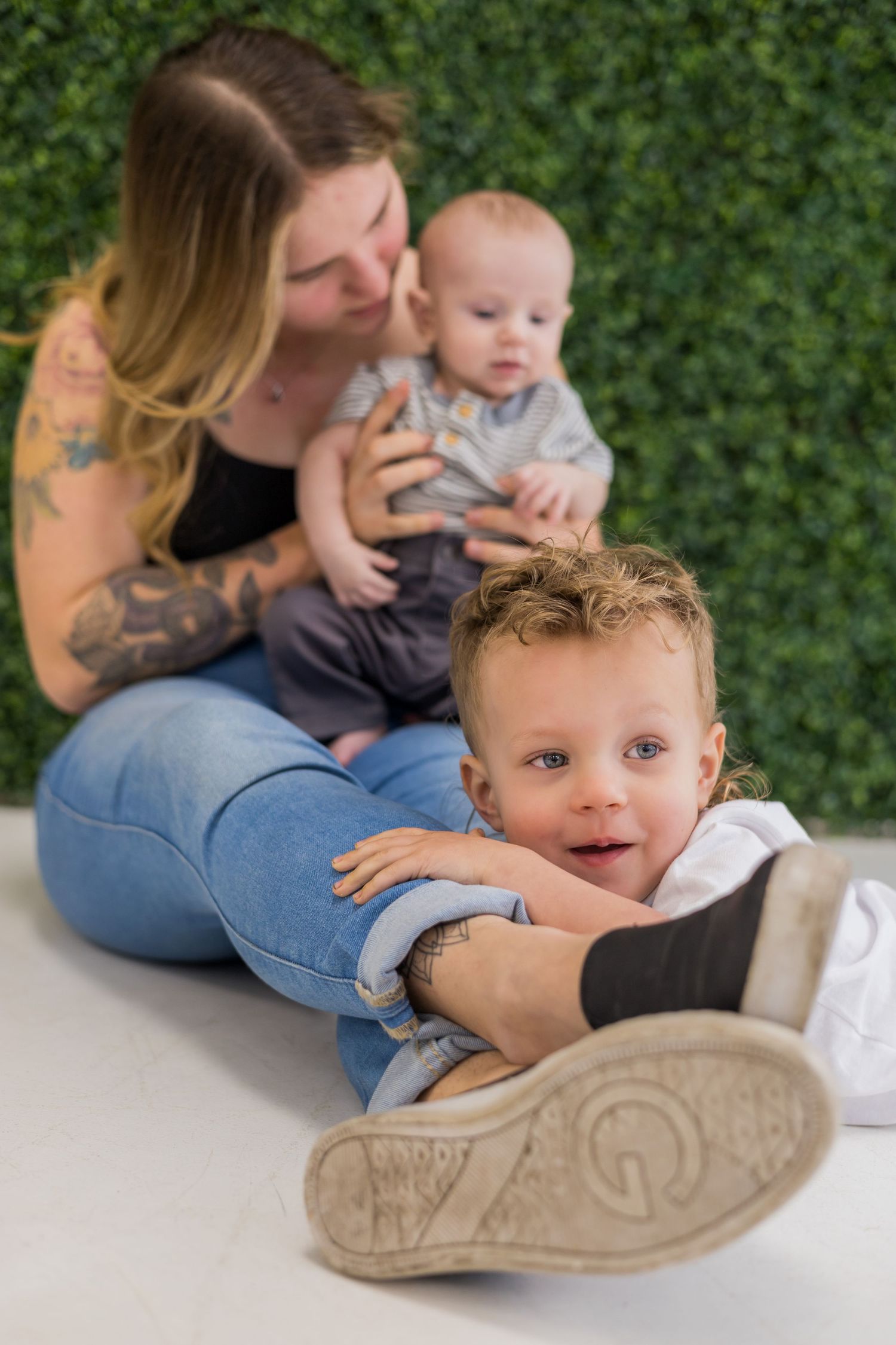 Candid floor poses of a family showing playful interactions against a green wall background.