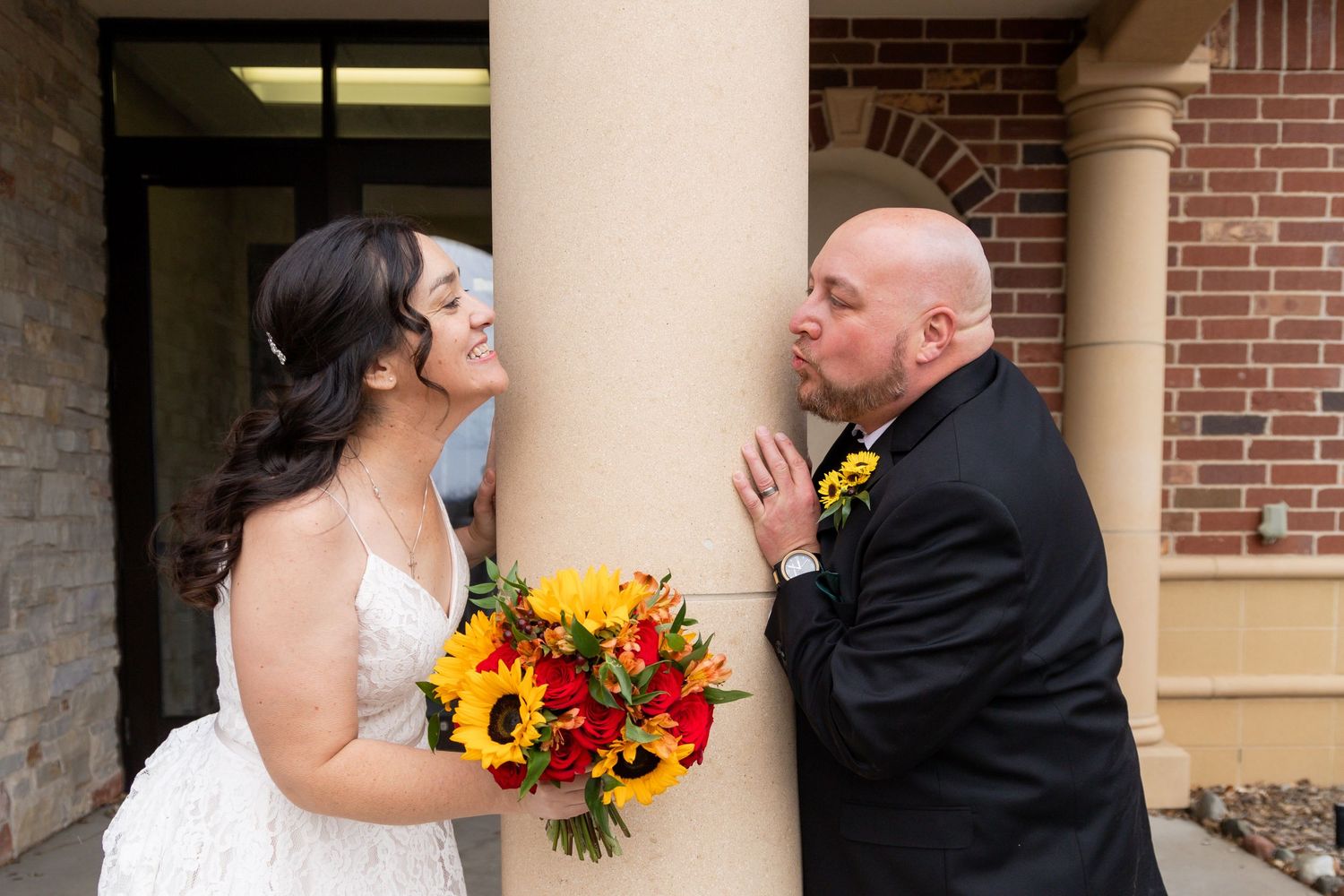A bride in white holds a vibrant sunflower bouquet while sharing an emotional moment.