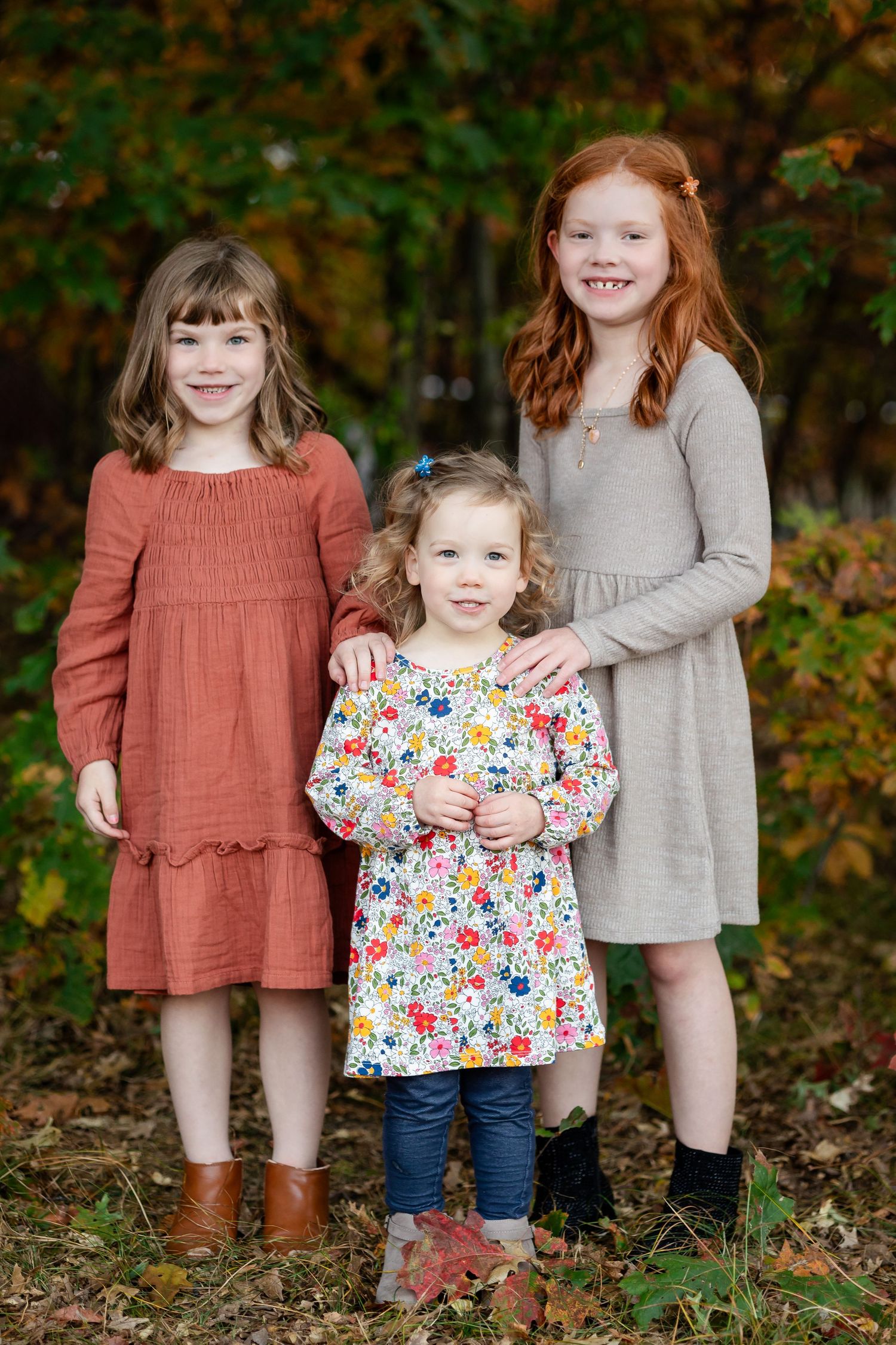 Close up view of children wearing coordinated fall outfits standing together in wooded setting.