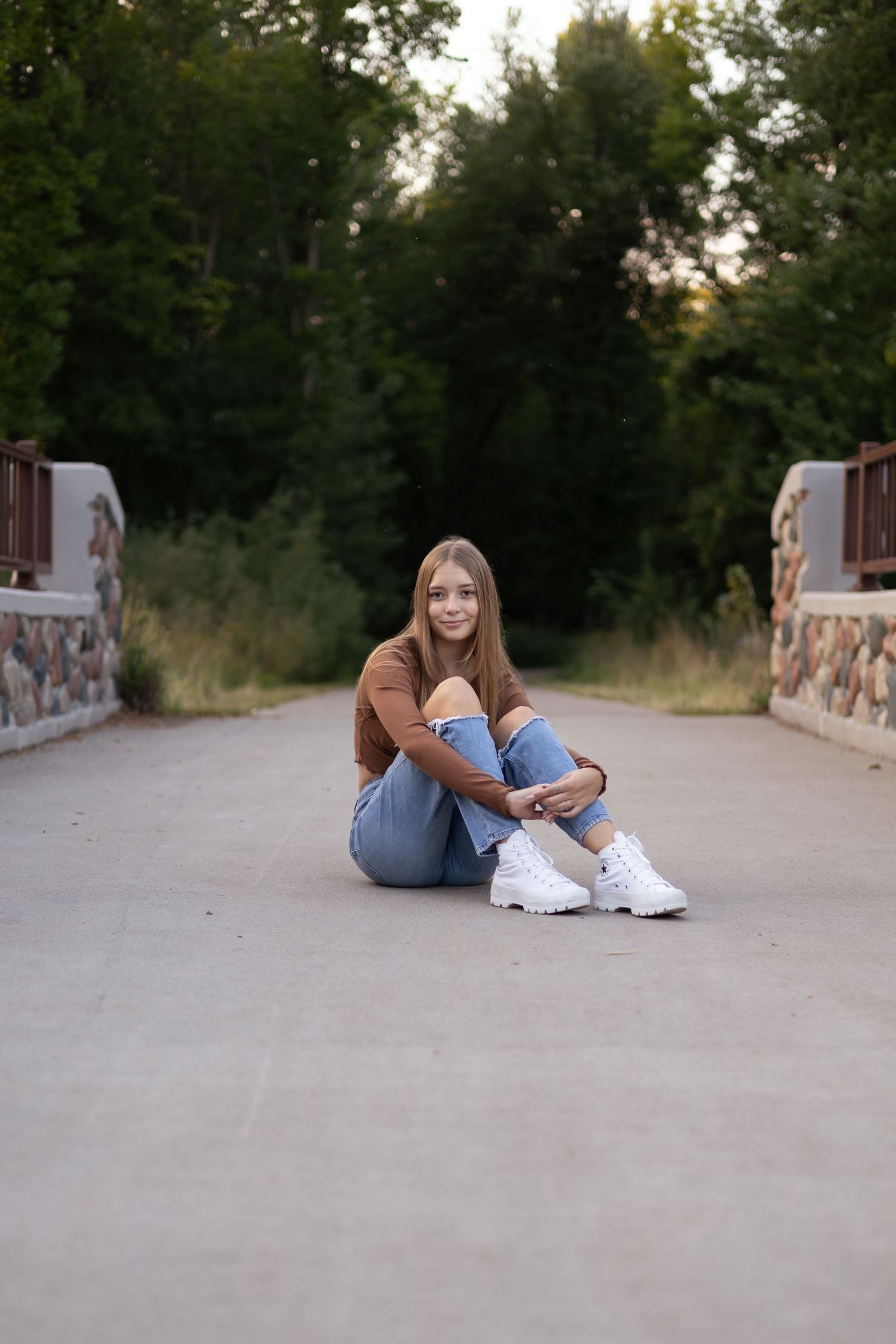 Person in casual attire lying on concrete ground with trees in background during golden hour.