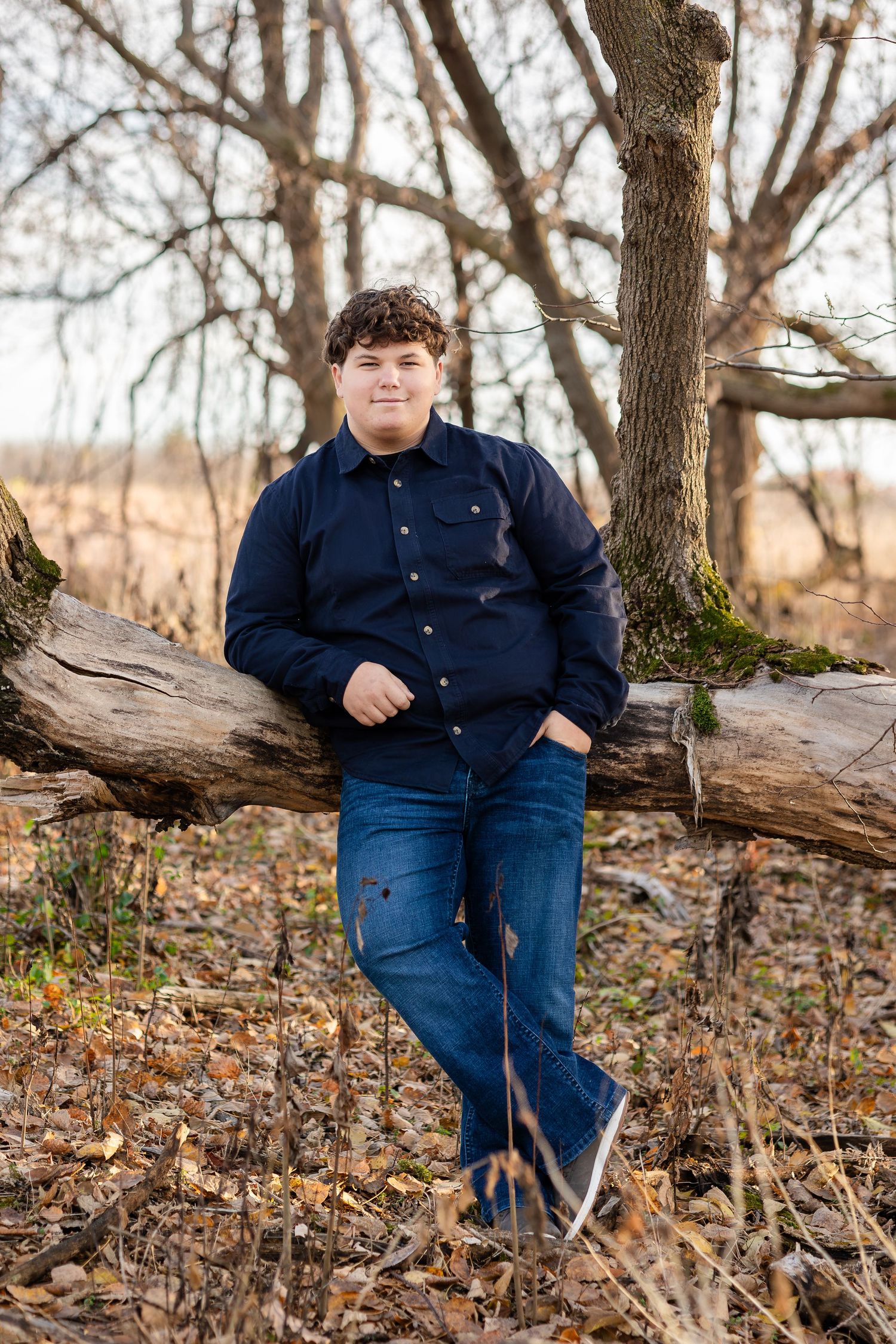 Casual outdoor portrait session among fallen trees and autumn leaves.