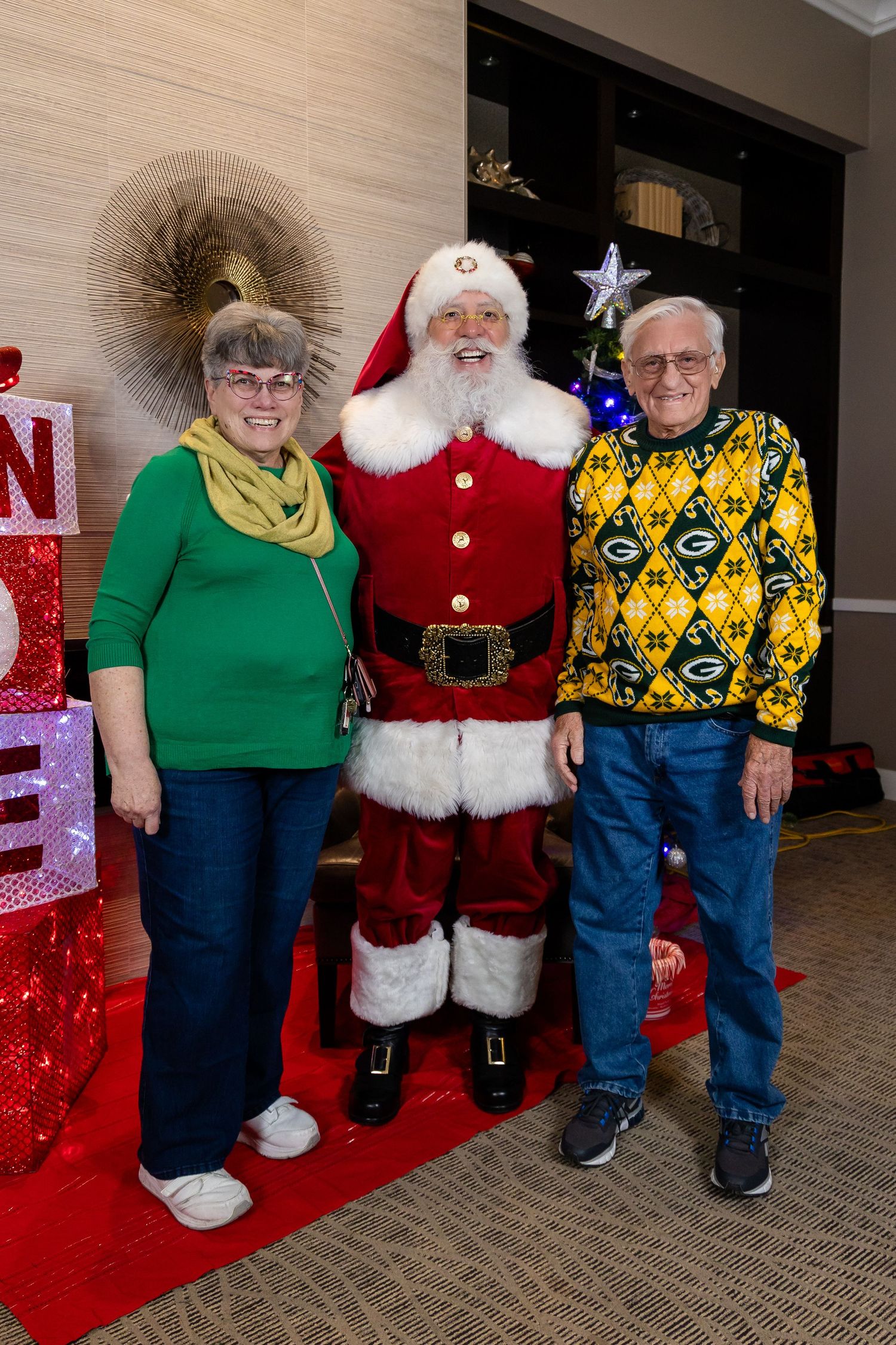 Holiday photo setup with festive decorations and bright red carpet.
