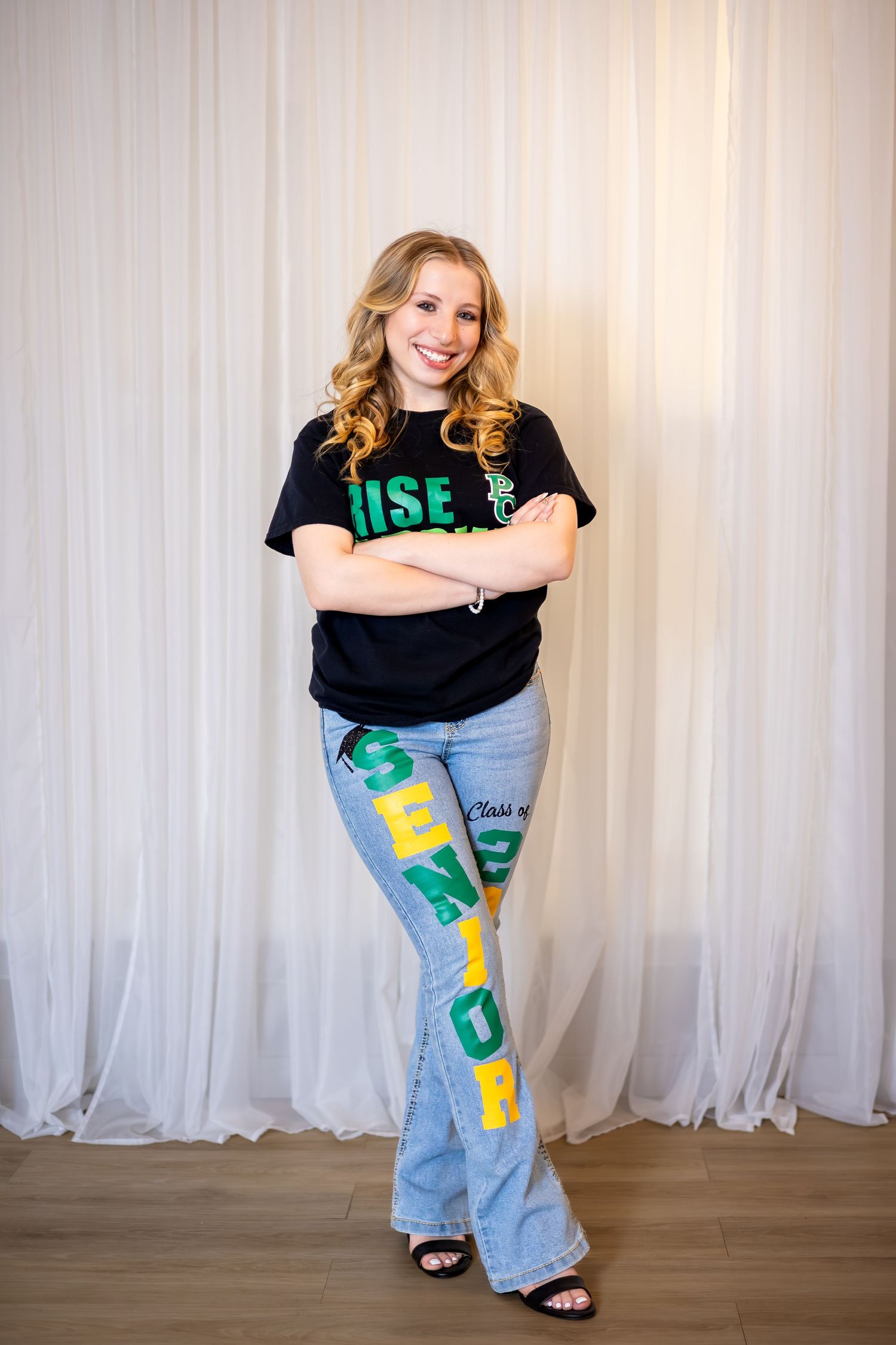 A series of five poses showing someone wearing a black t-shirt and painted denim jeans against a white curtain backdrop.