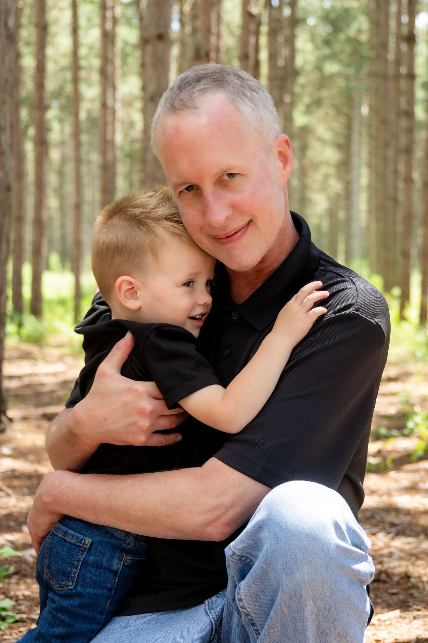 Tender moments captured in a wooded setting with black shirts and jeans.