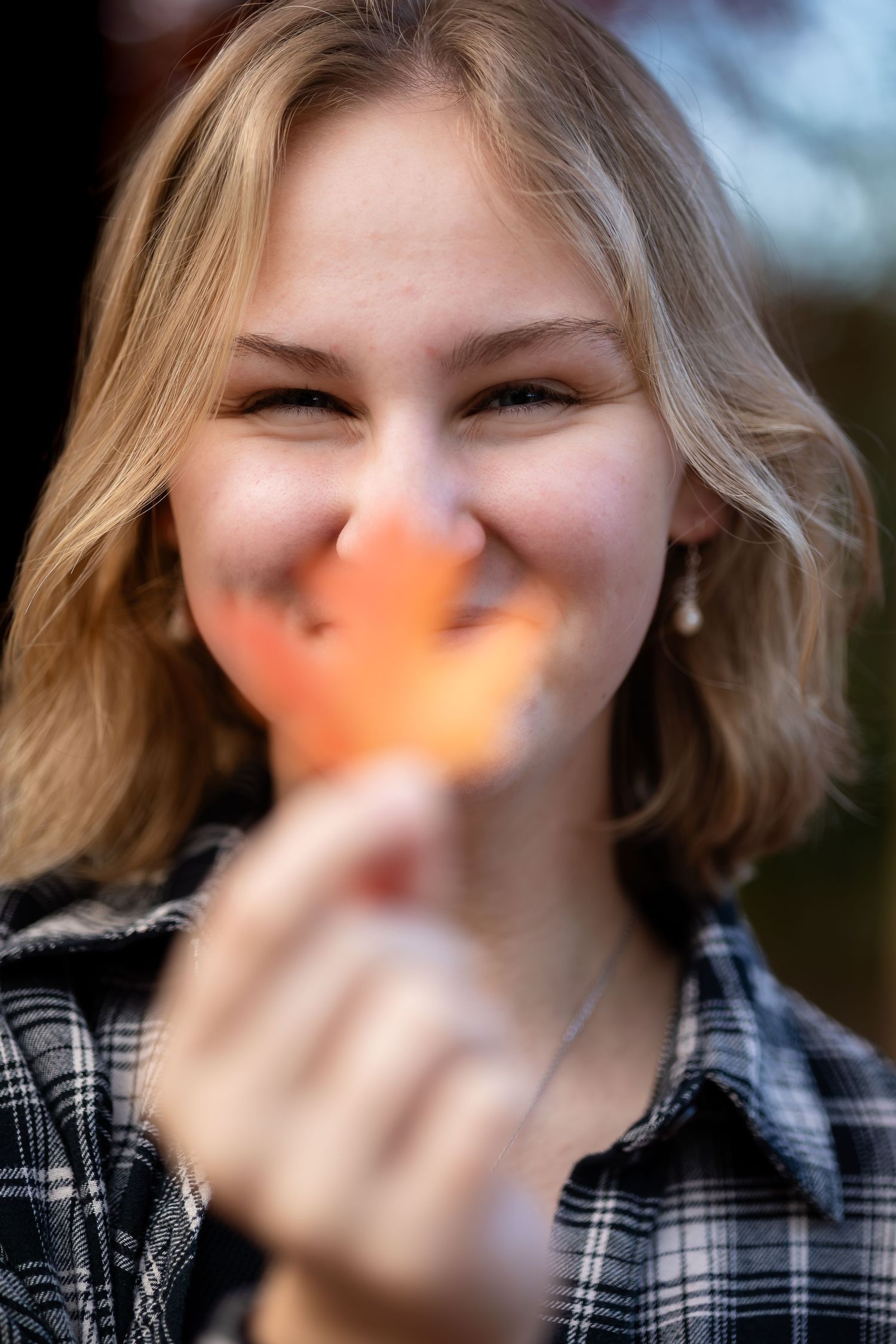 A series of photos showing someone in a plaid shirt holding an autumn leaf in front of their face outdoors.