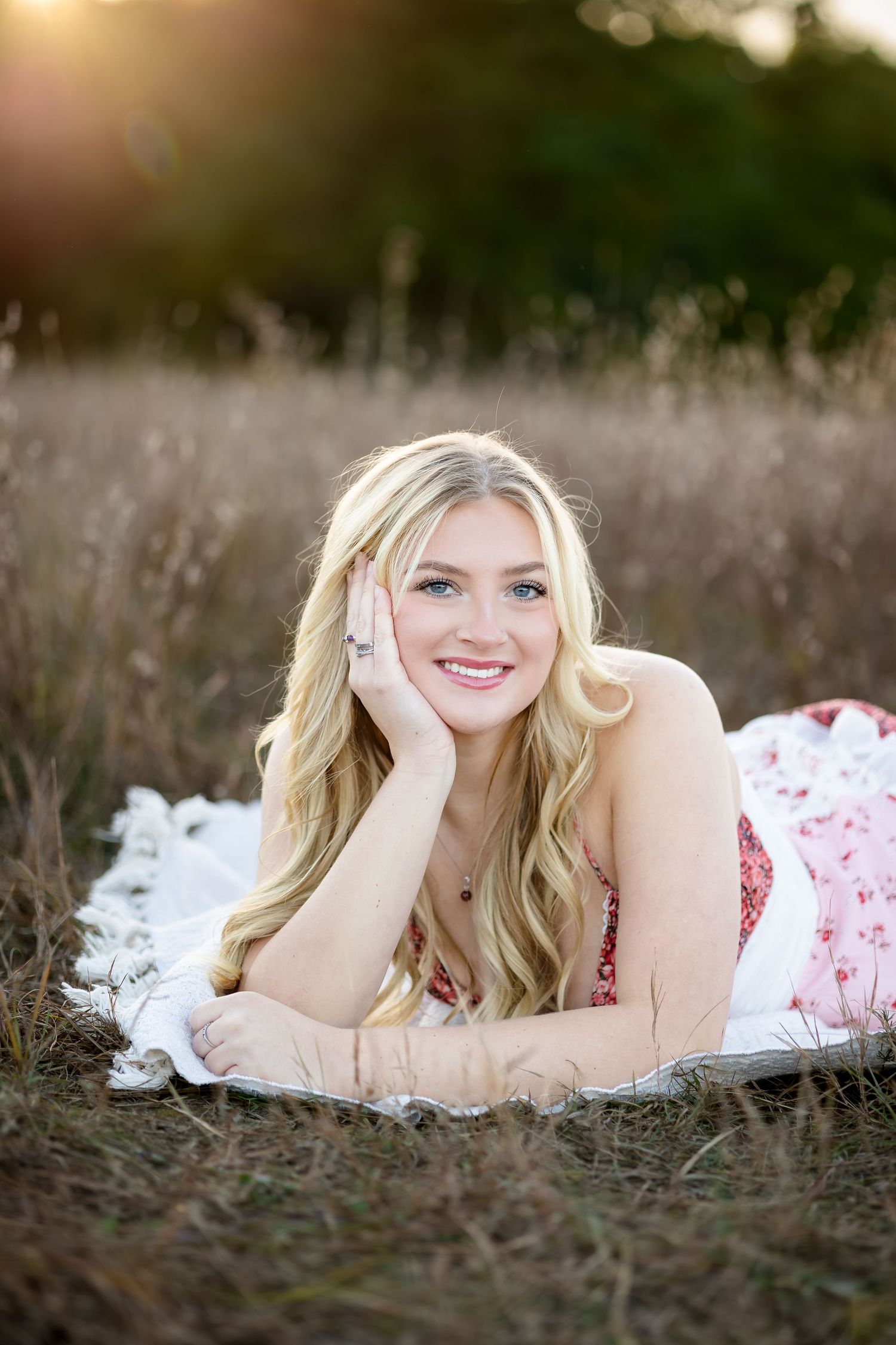 Outdoor photo session featuring a white and red floral dress in a natural setting at golden hour.