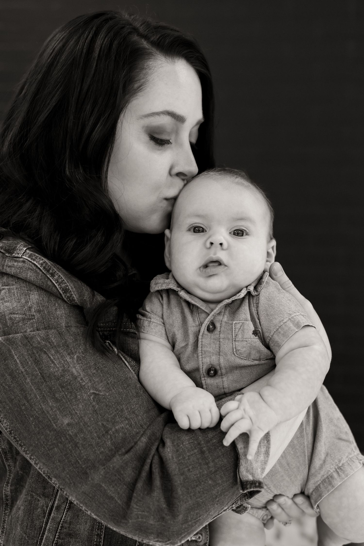 Black and white portrait of tender moment between parent and baby in denim.