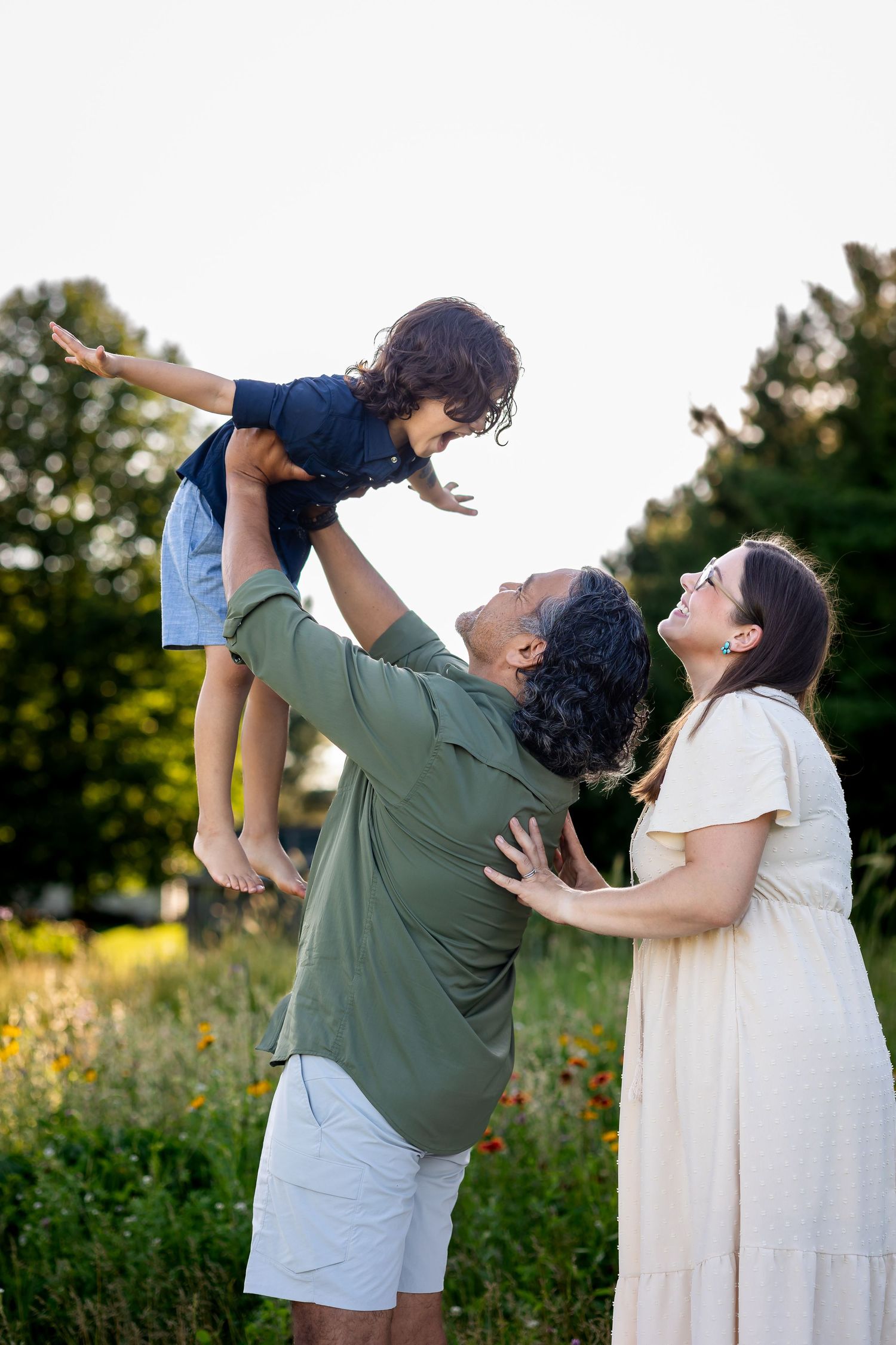 Playful family photos showing joyful moments in a field of wildflowers at sunset.