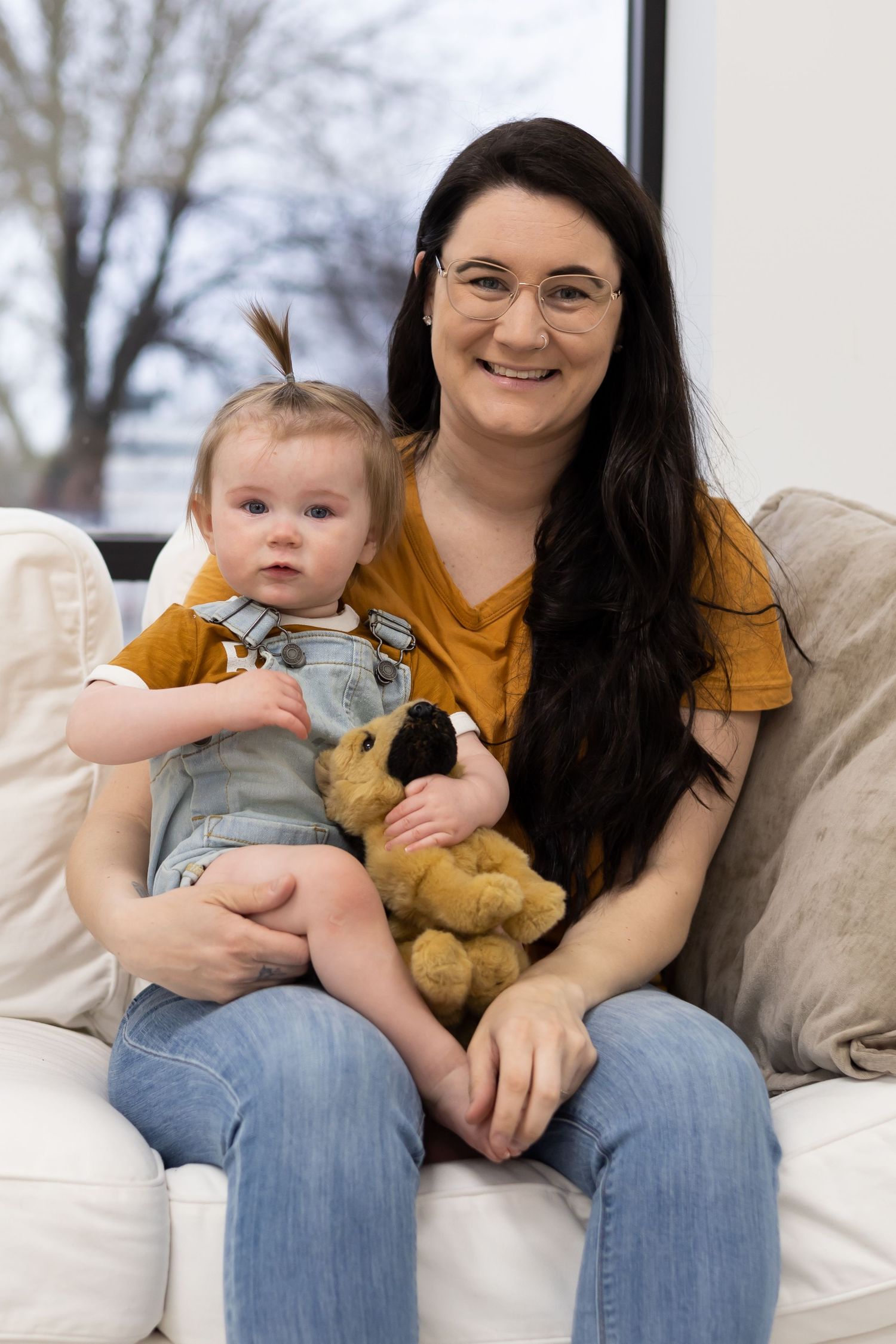 Casual indoor family portrait on a beige couch wearing mustard and denim.
