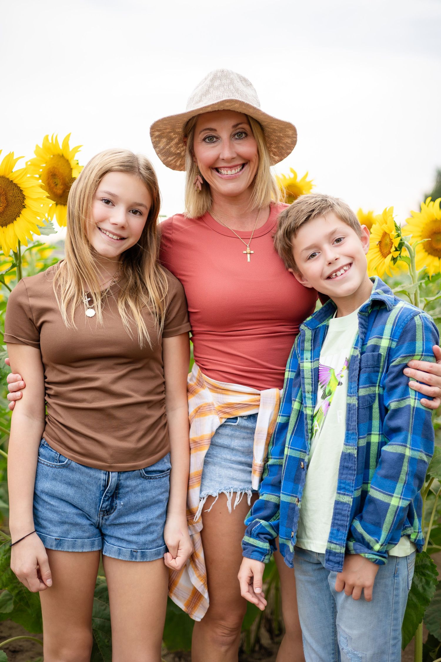 A group poses together in casual summer outfits against a backdrop of bright sunflowers.