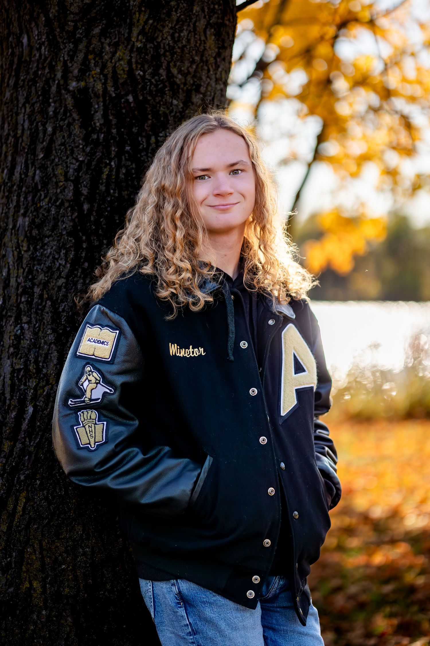 A varsity letterman jacket being modeled outdoors during golden autumn sunset lighting.