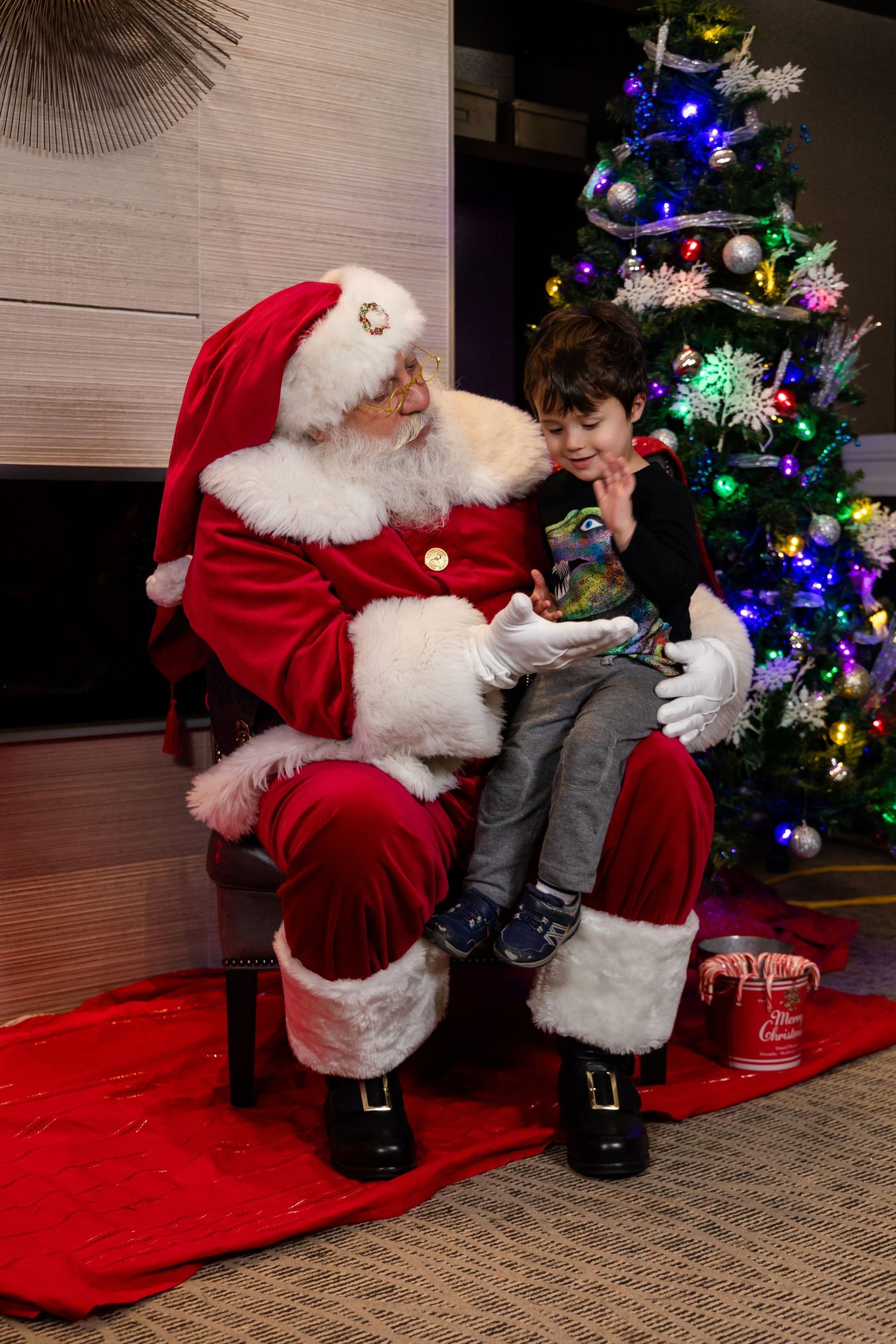 Santa Claus shares a special moment near a festive Christmas tree with twinkling lights.