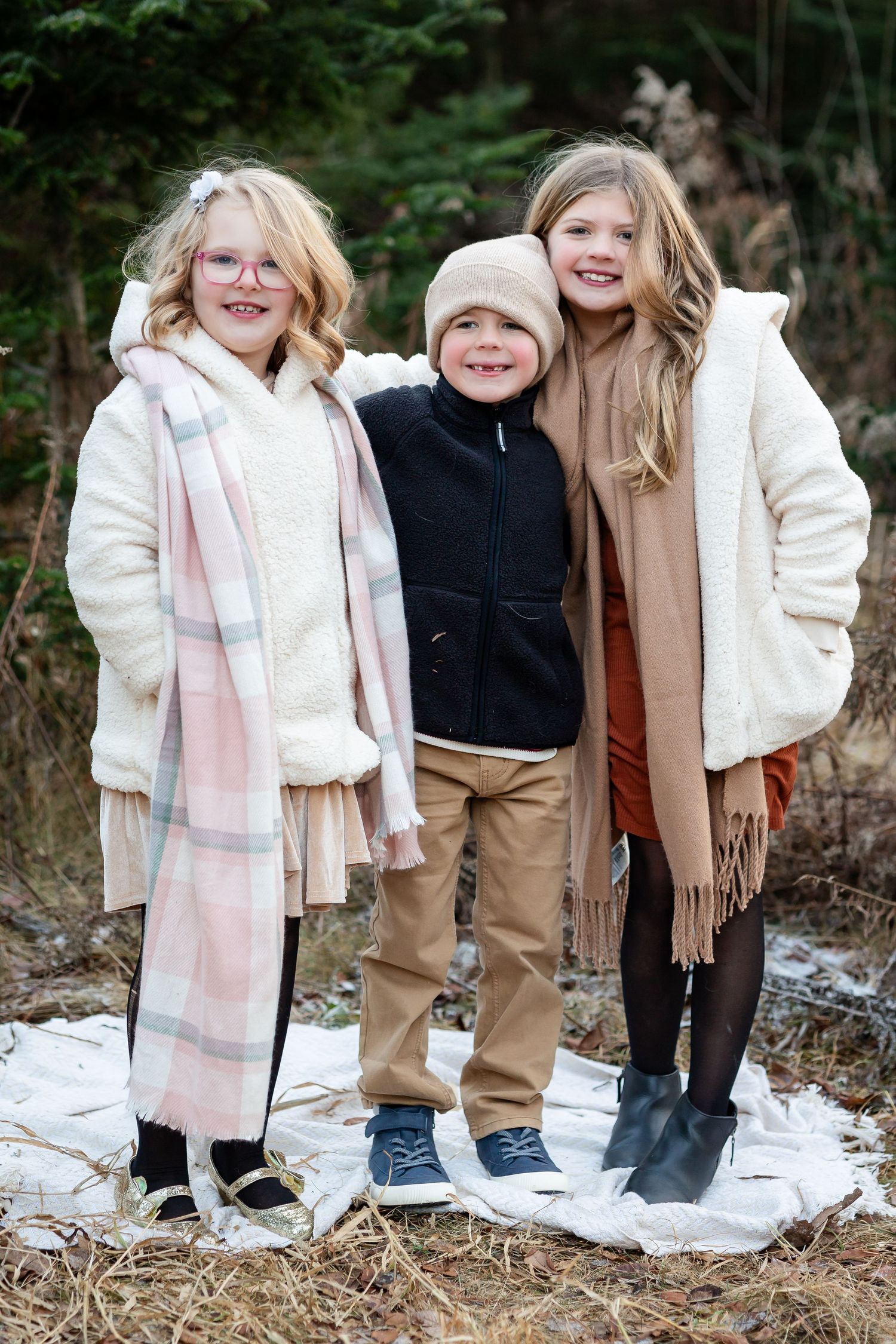 Group wearing winter coats and scarves poses together in snowy outdoor setting.