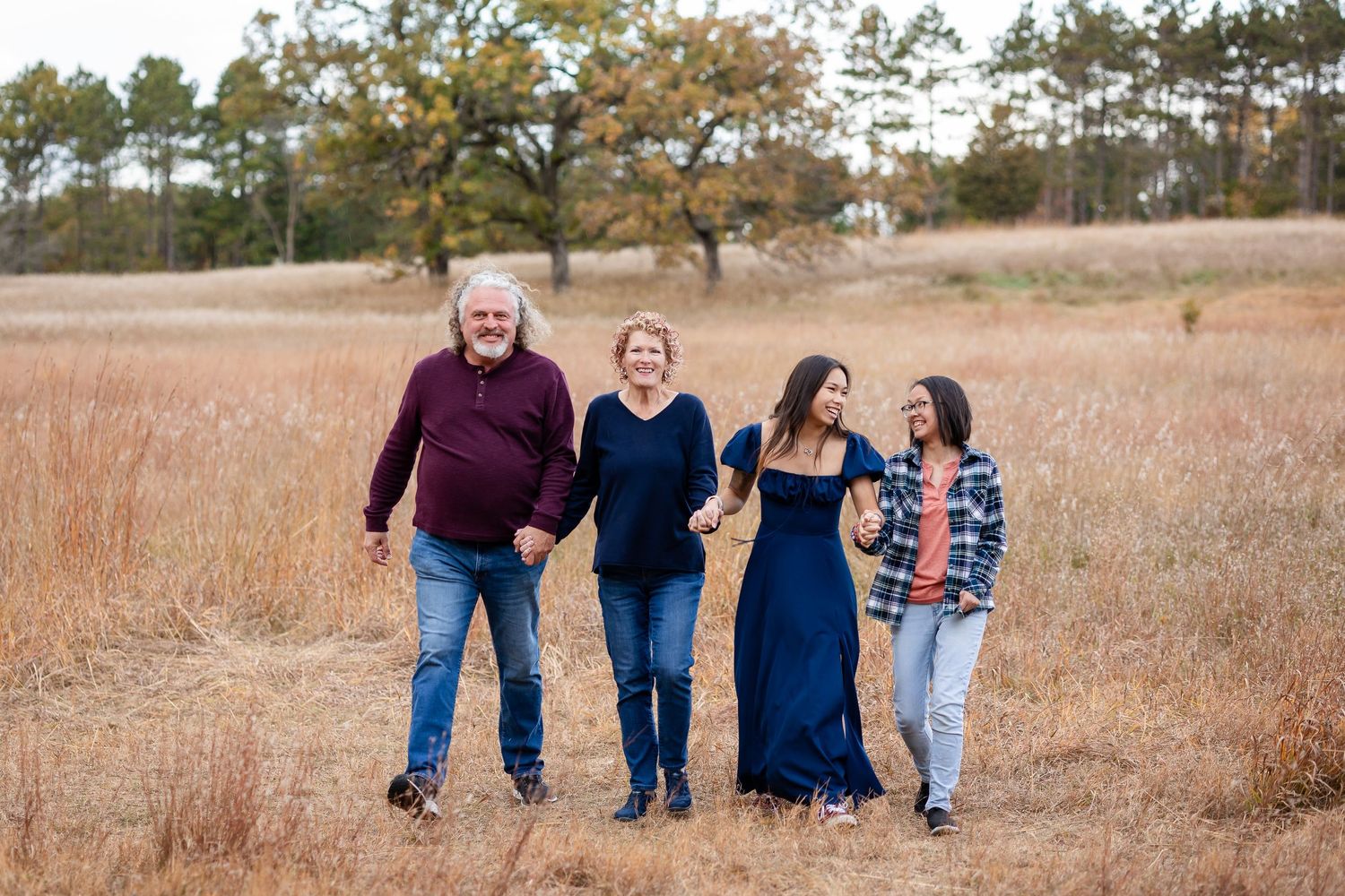 Family walking together through a golden field during an autumn photoshoot.