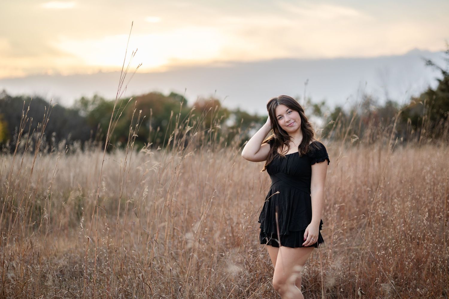 Artistic portrait in a field of tall grass during golden hour.