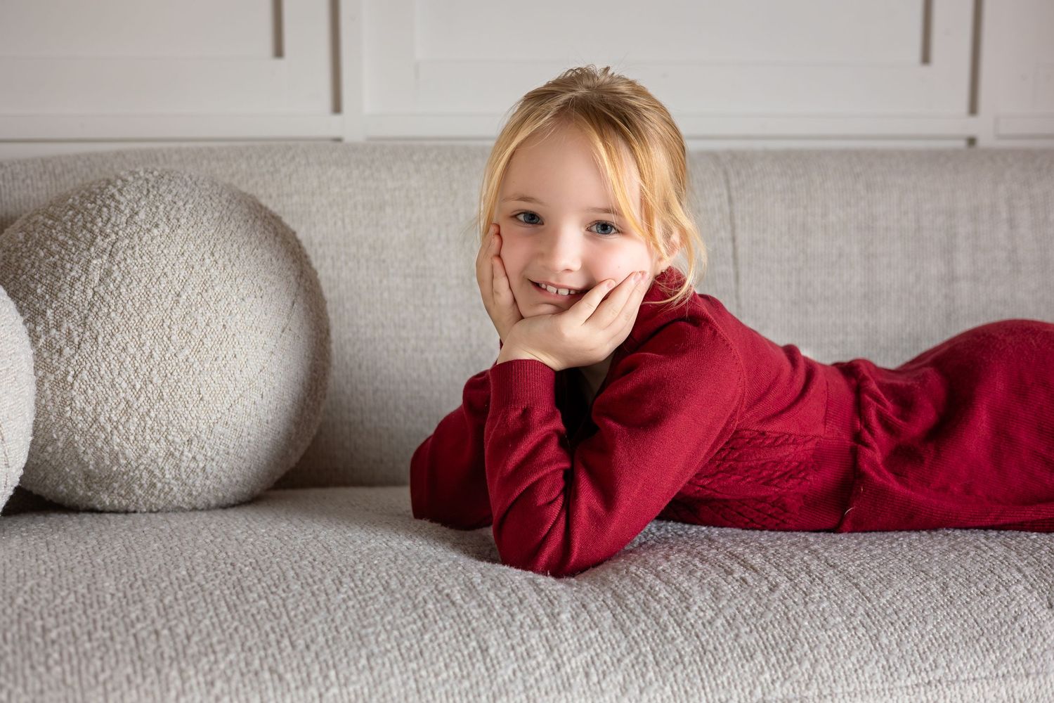 Series of relaxed poses on white couch showing playful moments in minimalist setting.