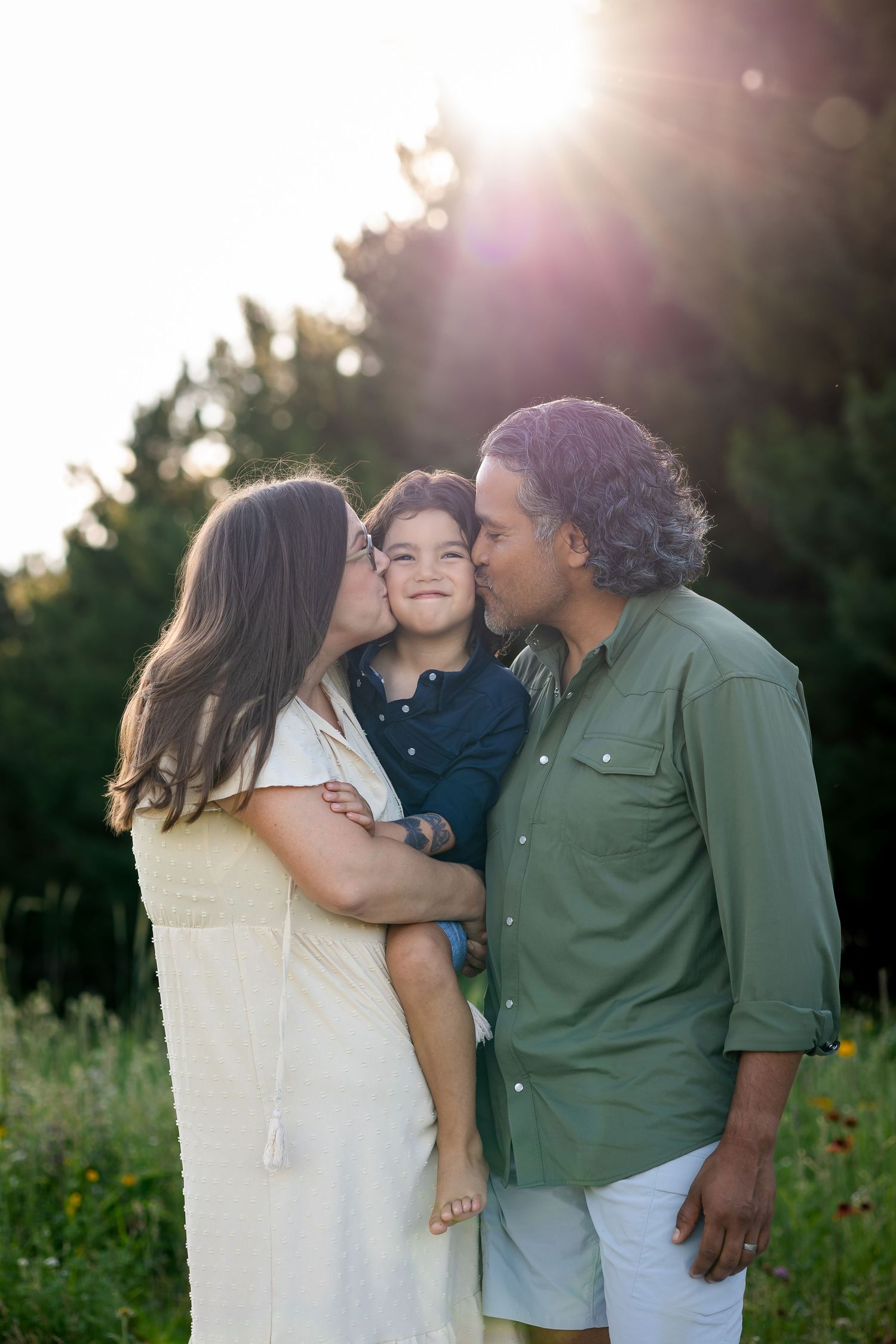 A loving family shares a tender moment together in a sunlit meadow during golden hour.