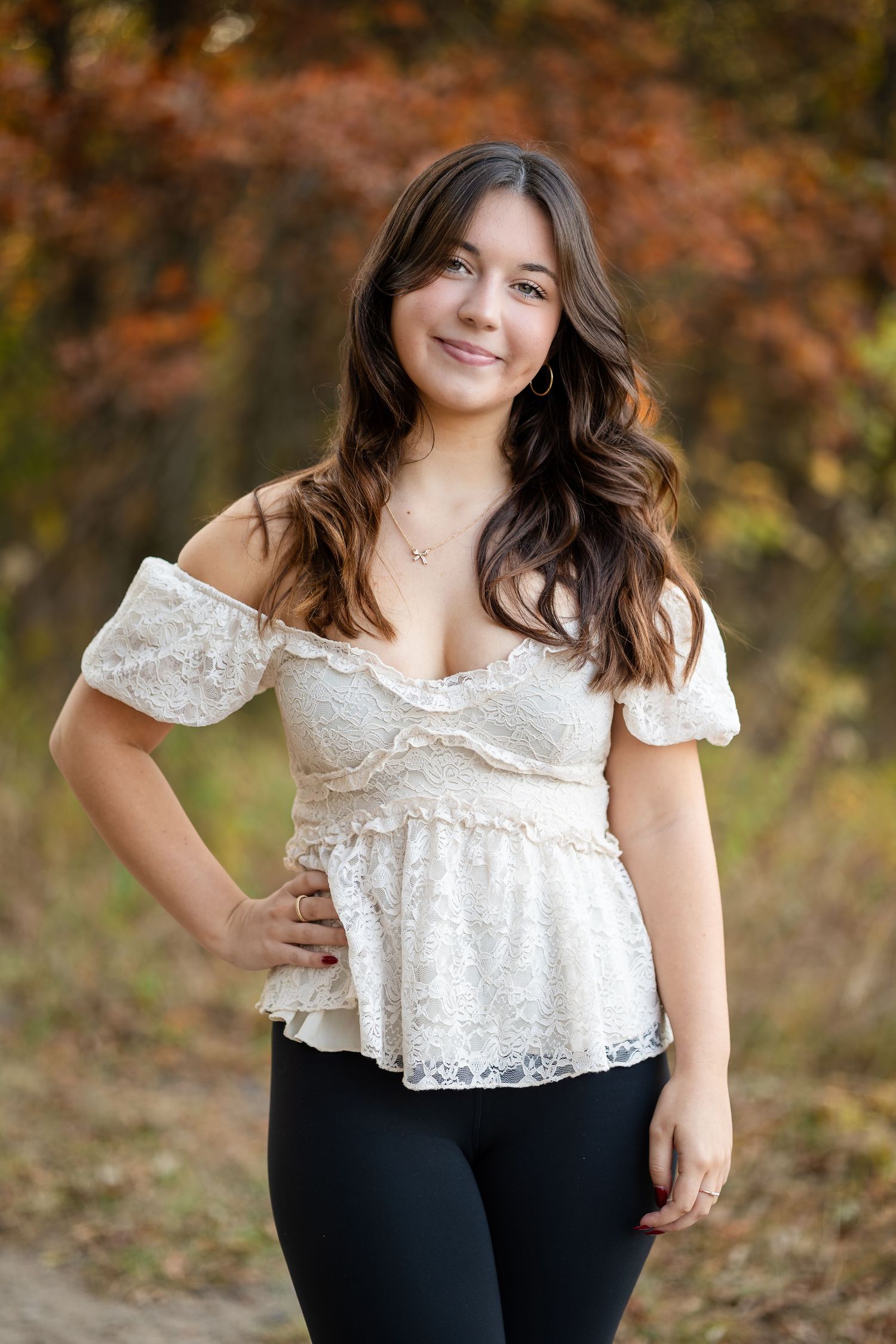 Autumn portrait session featuring white lace top against fall foliage background.