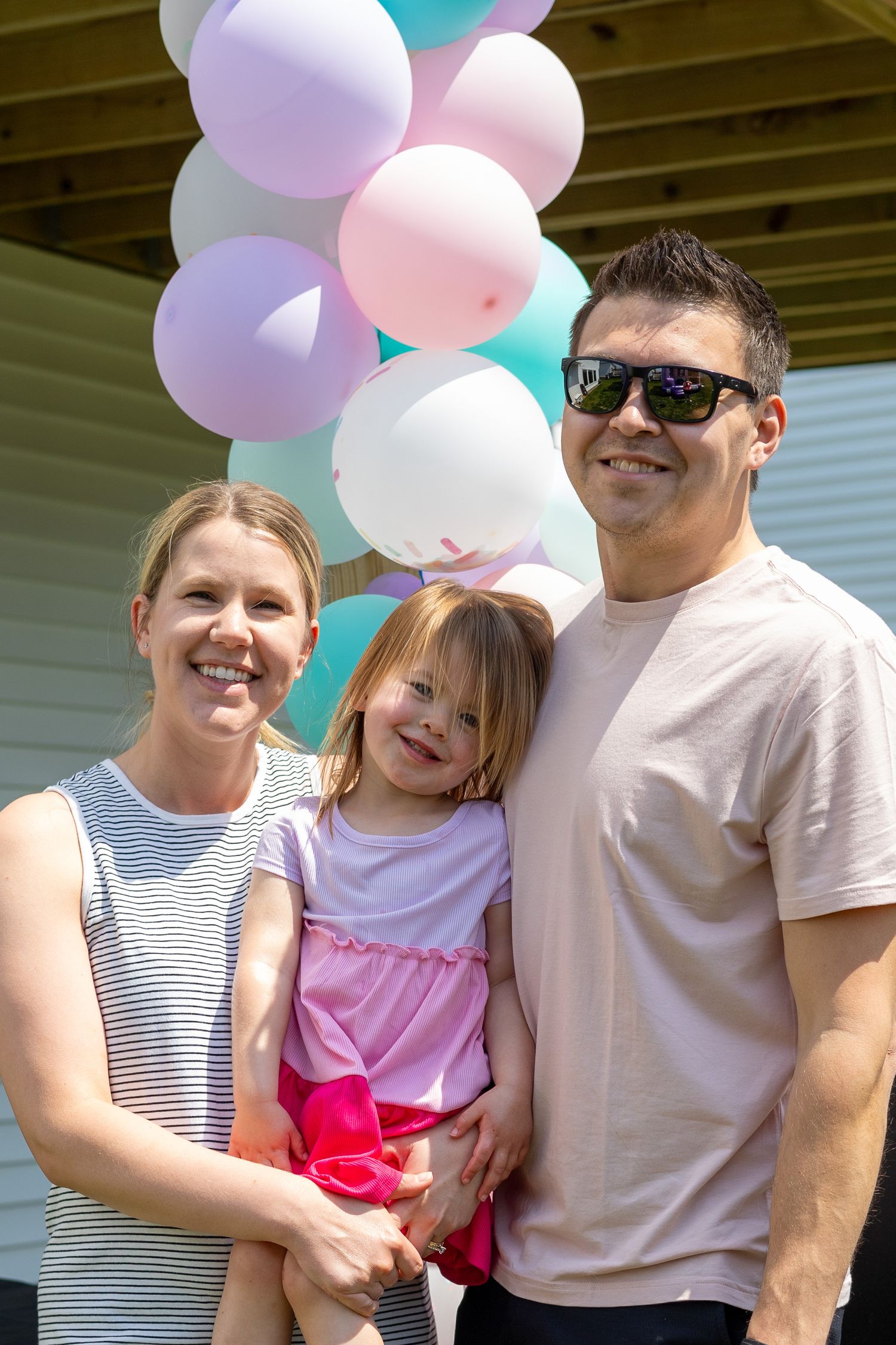 Family gathering outdoors with pink and blue balloons decorating the space.