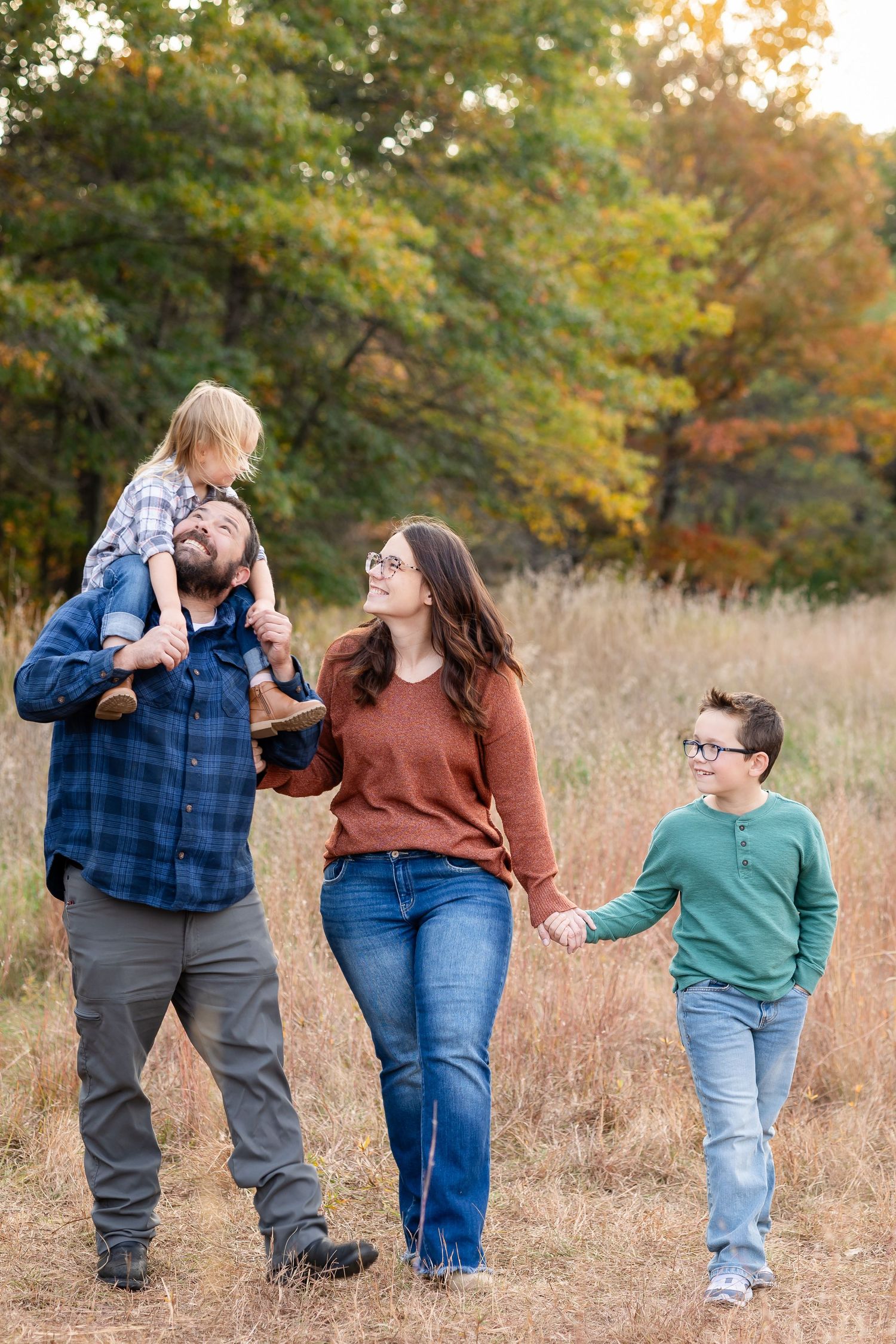 Family walking together through a golden field during fall season.
