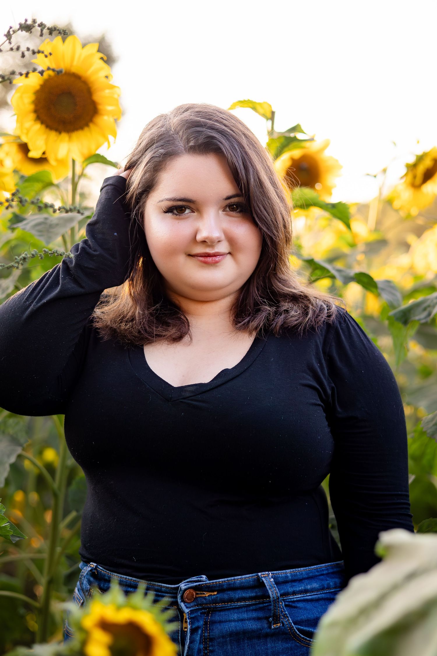 Outdoor photoshoot in sunflower garden with natural lighting and casual autumn attire.