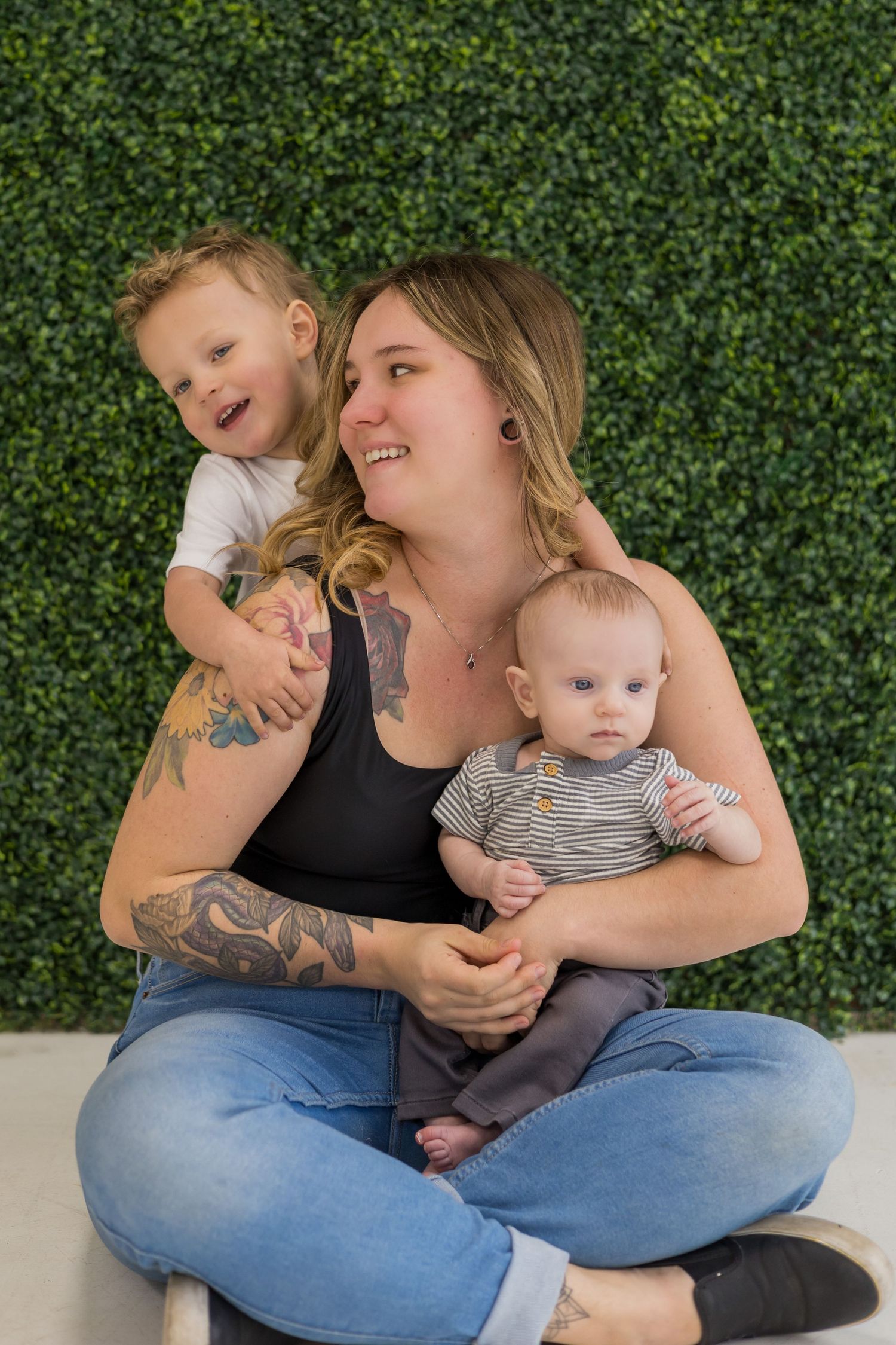 Intimate family moments captured while sitting on floor against a green foliage backdrop.