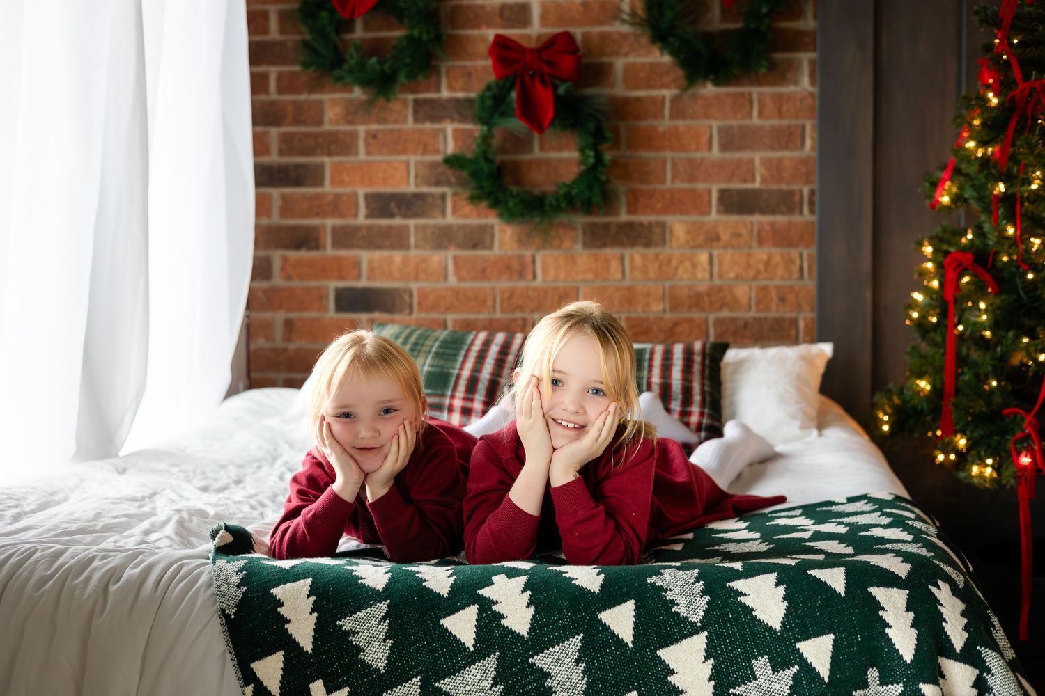 Holiday themed photos of children on couch with Christmas decorations and brick wall backdrop.