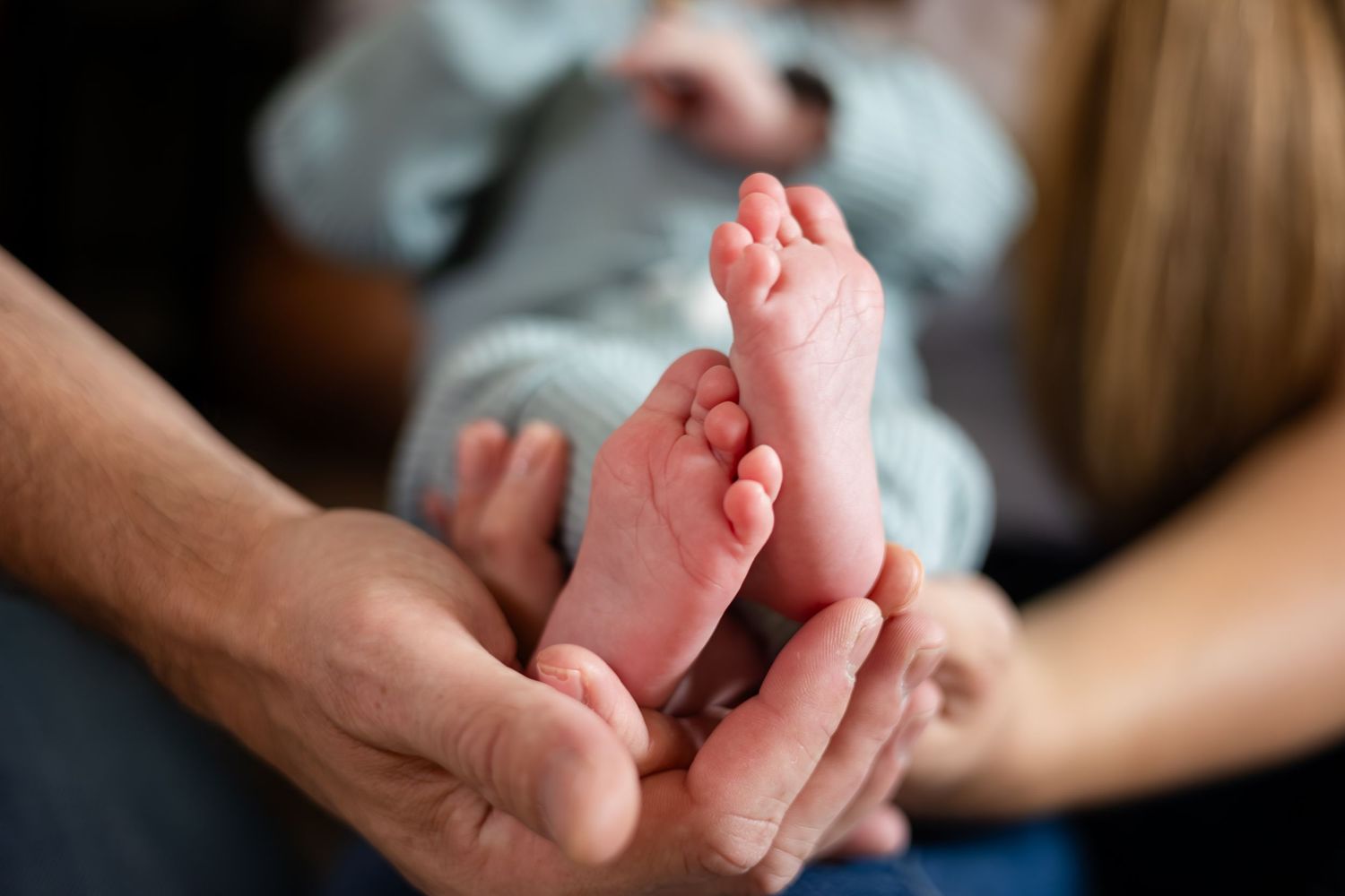 Close up view of tiny baby feet being held gently by caring hands.