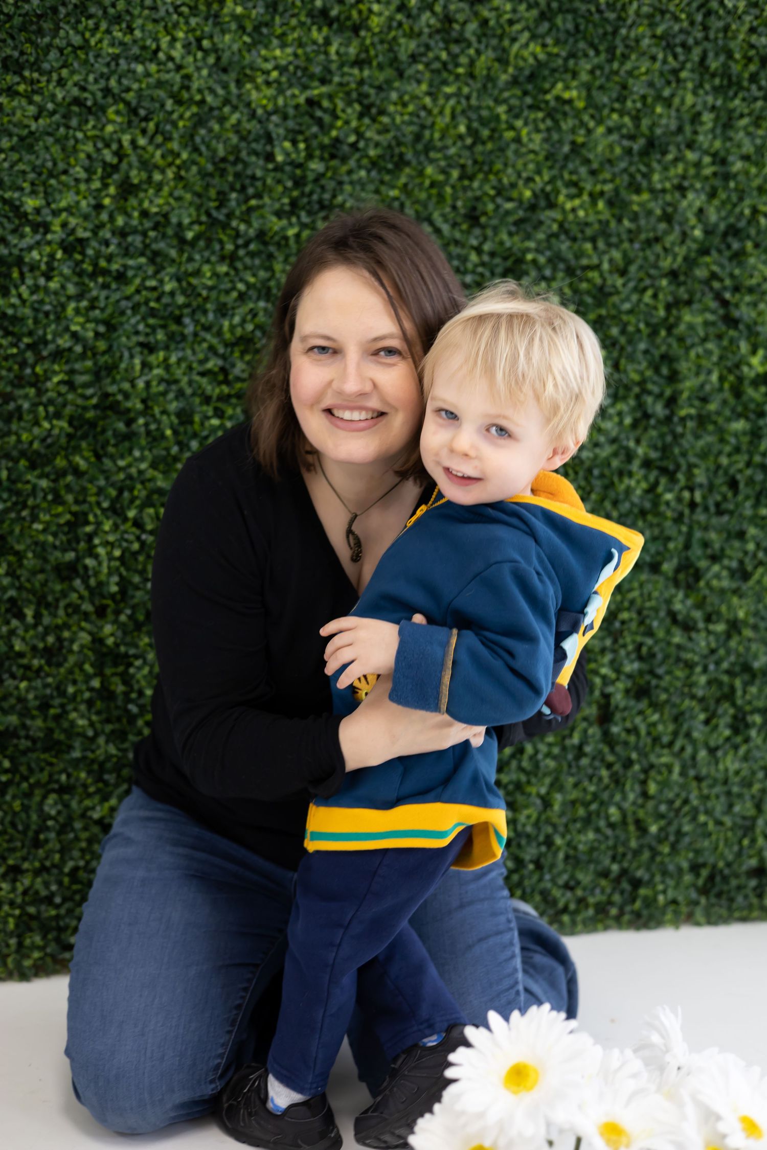 A cheerful portrait against green foliage featuring casual style and white daisies.
