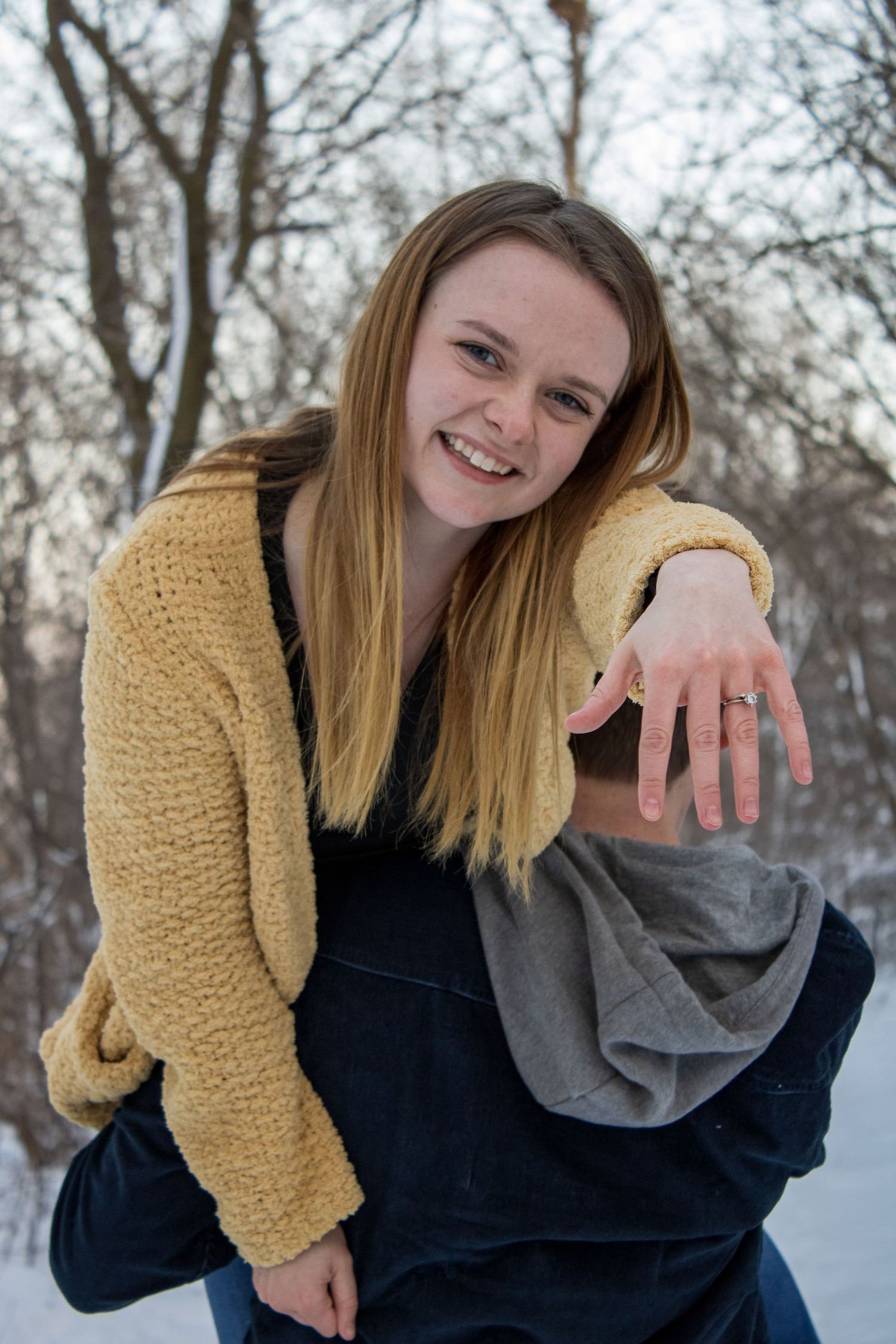 A sequence showing a couple sharing a joyful moment while displaying an engagement ring in the snow.