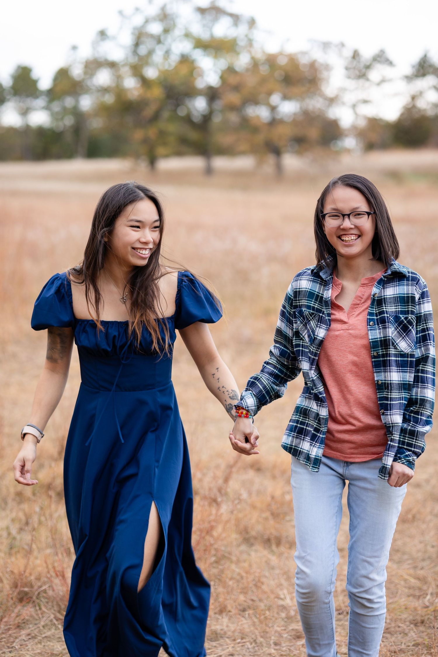 Friends in coordinating blue and plaid outfits playfully posing in a autumn field.