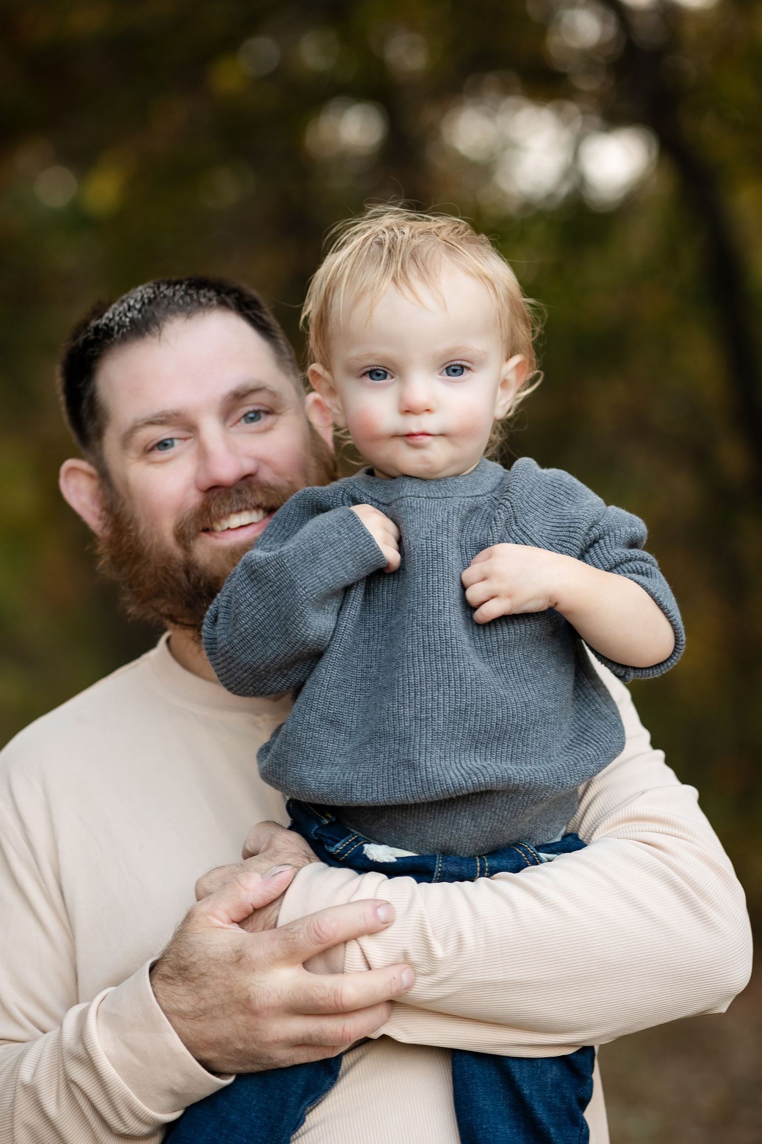 Playful outdoor moments between parent and child wearing gray and cream colored clothing.