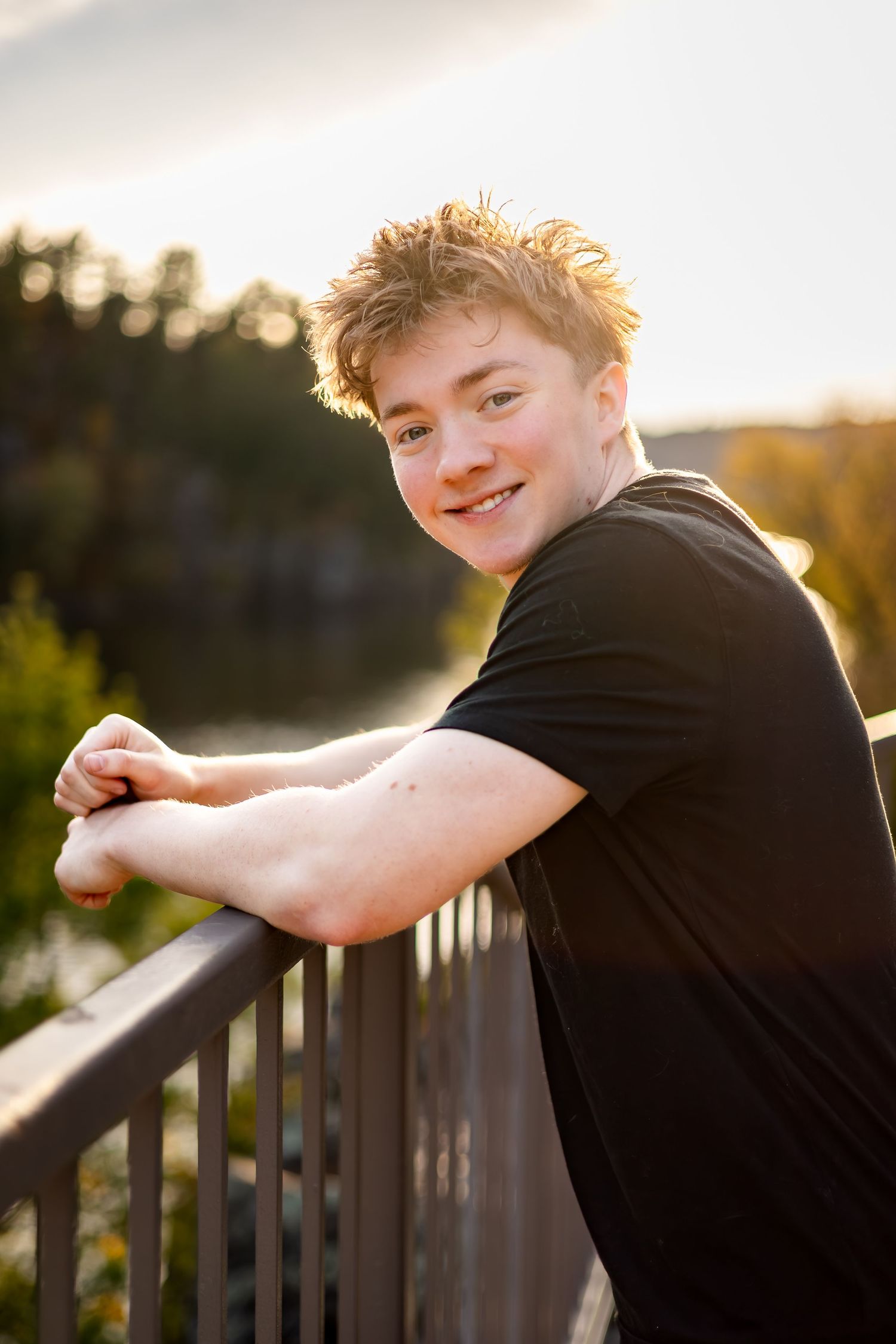 A young person in a black t-shirt leans against a railing at sunset, captured in a series of candid poses.