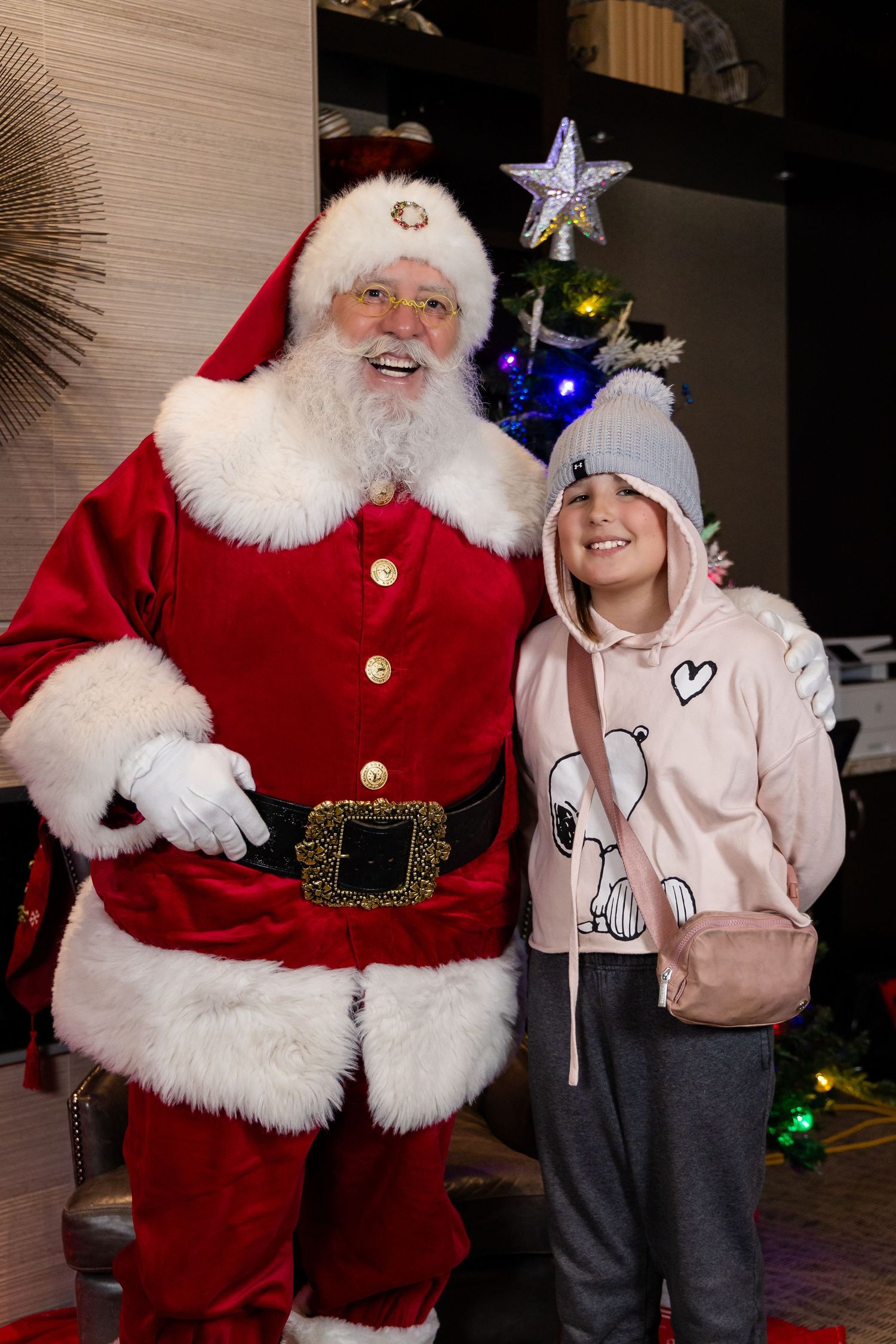 A cheerful holiday scene with Santa Claus next to a Christmas tree with twinkling lights.