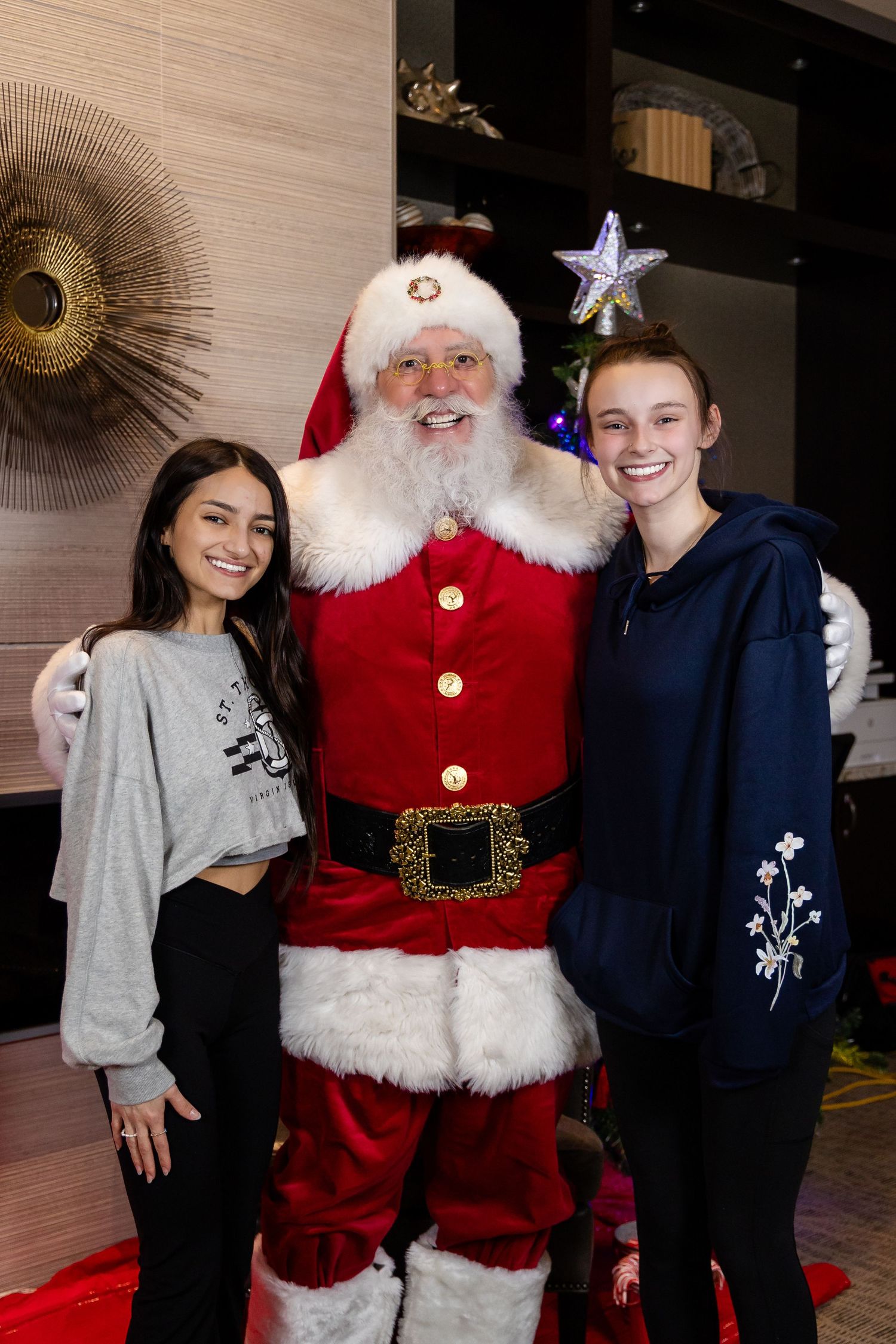 A holiday photo session with Santa Claus in his traditional attire next to a decorated Christmas tree.