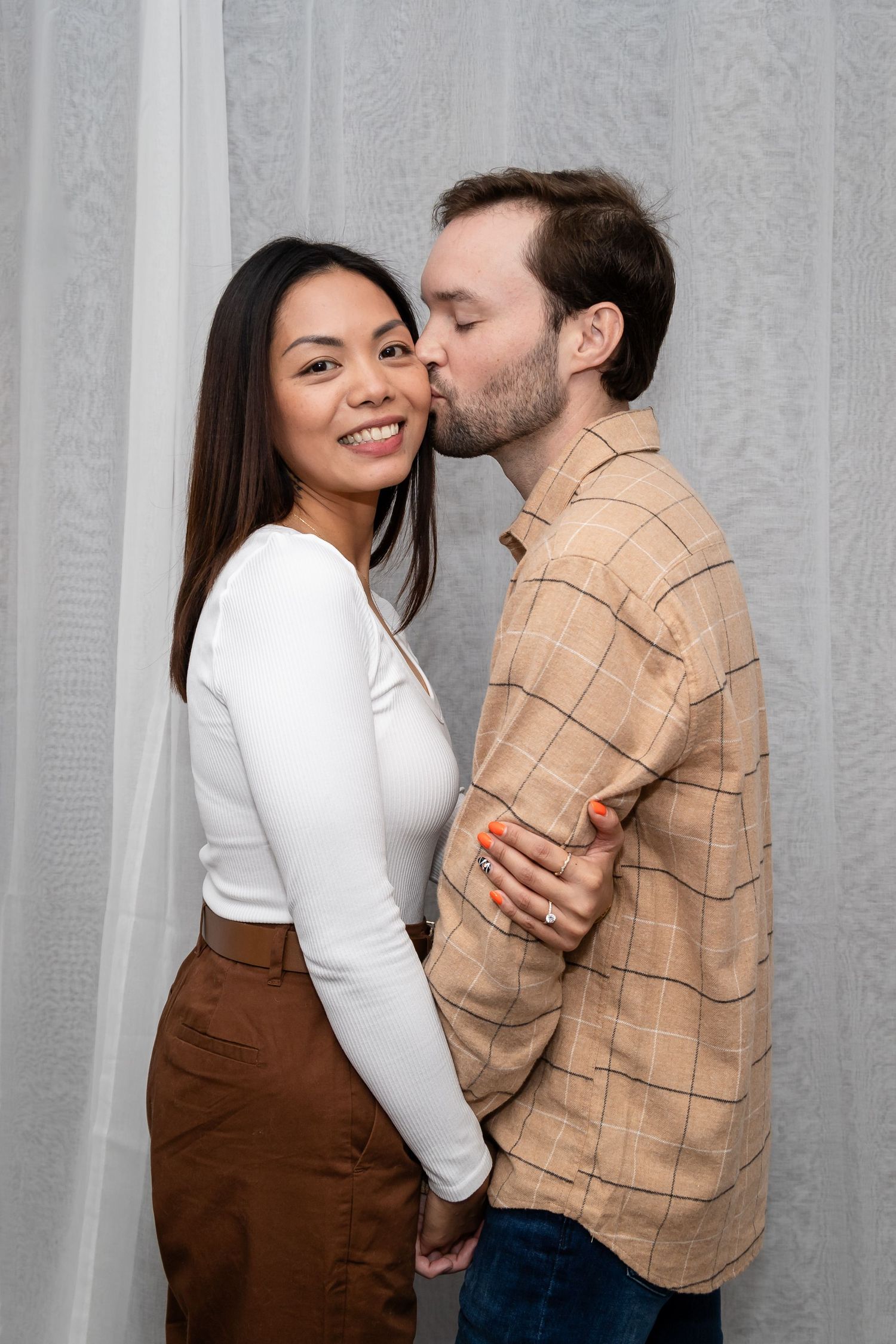 A couple embraces and shares tender moments against a grey backdrop.