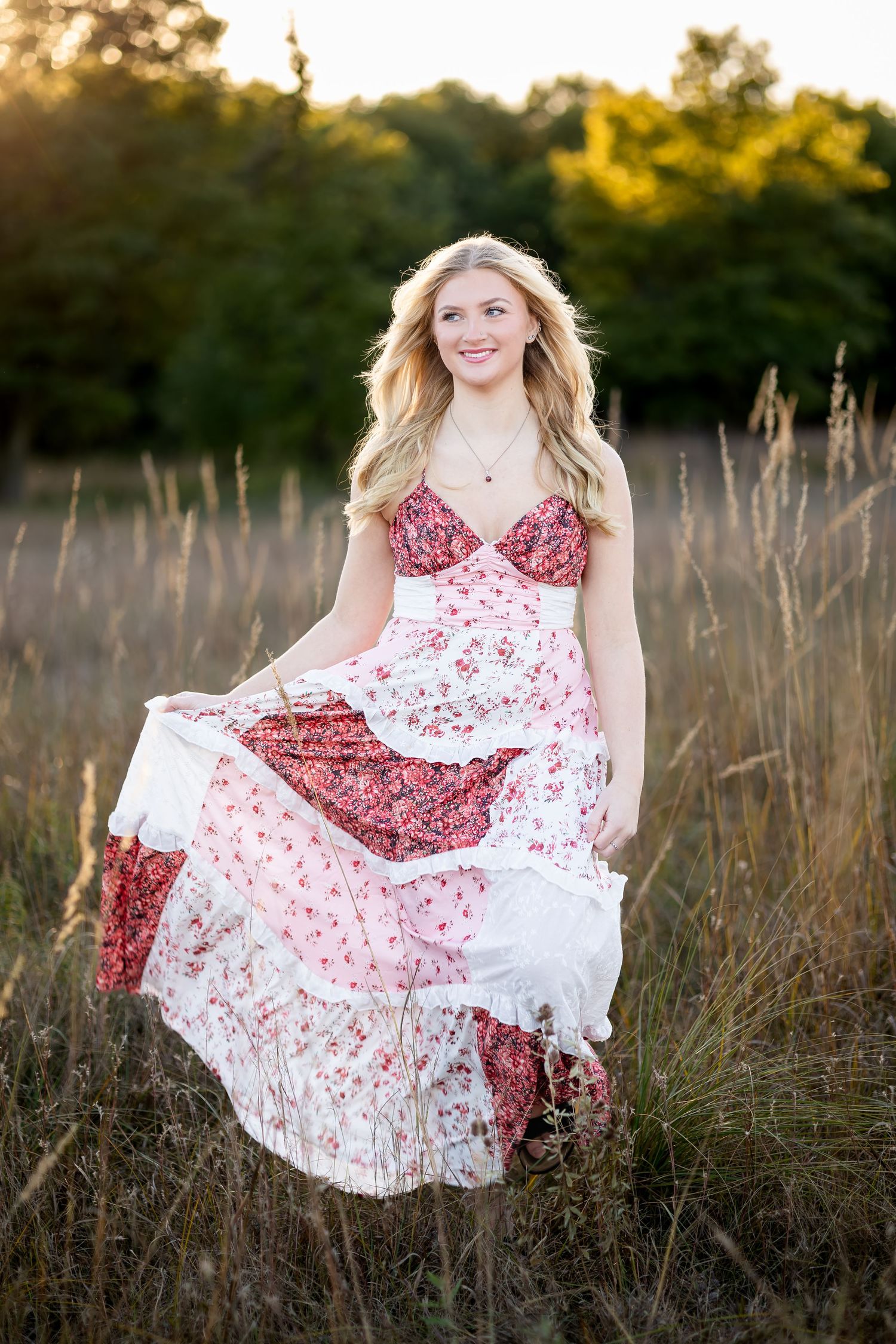A flowy red and white floral dress twirls gracefully in a golden field during sunset.