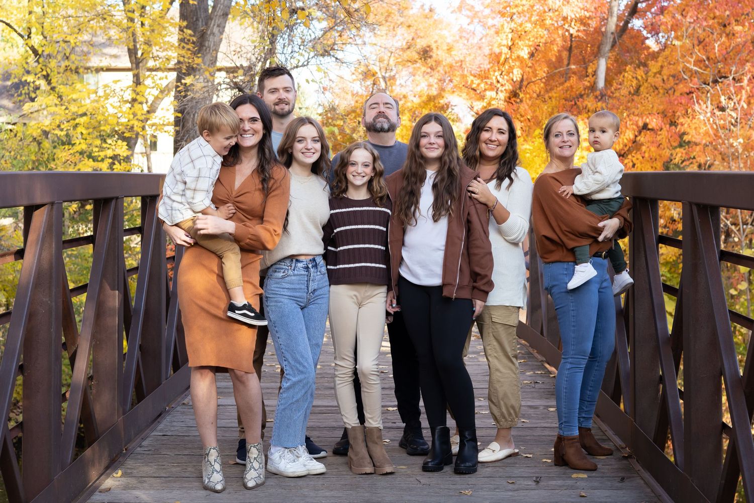 Large group photo on wooden bridge surrounded by vibrant autumn foliage.