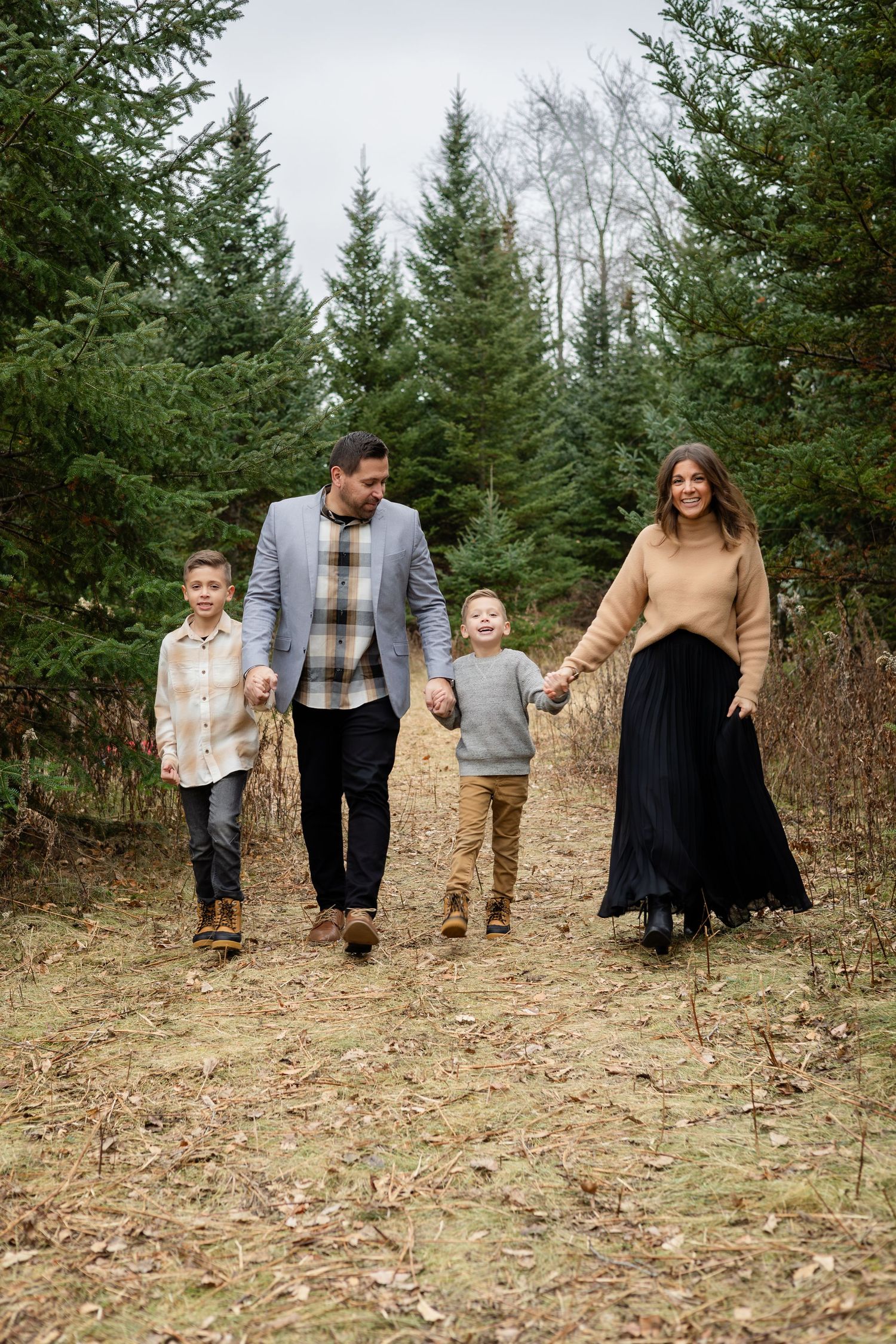 Family members walk hand-in-hand through a natural clearing with pine trees in the background.