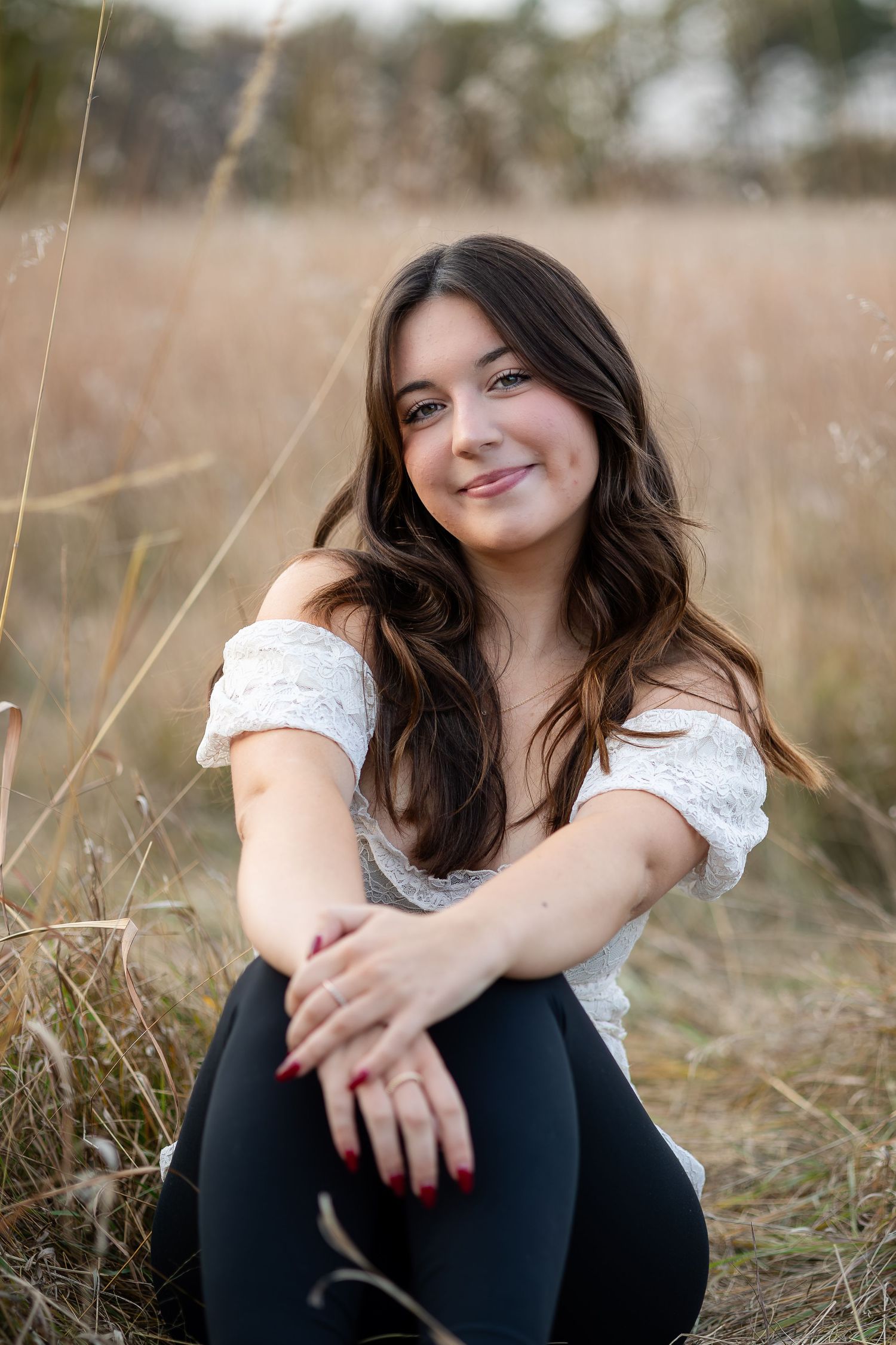Casual outdoor portrait session in grassy field during golden hour.
