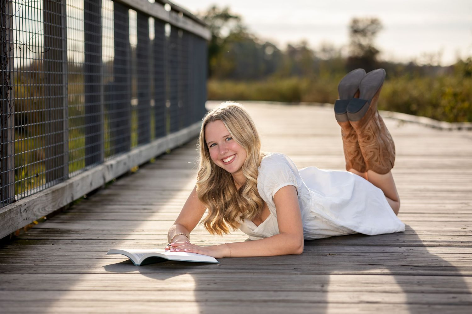 A sequence of photos showing someone lying on a wooden boardwalk in different relaxed poses at sunset.