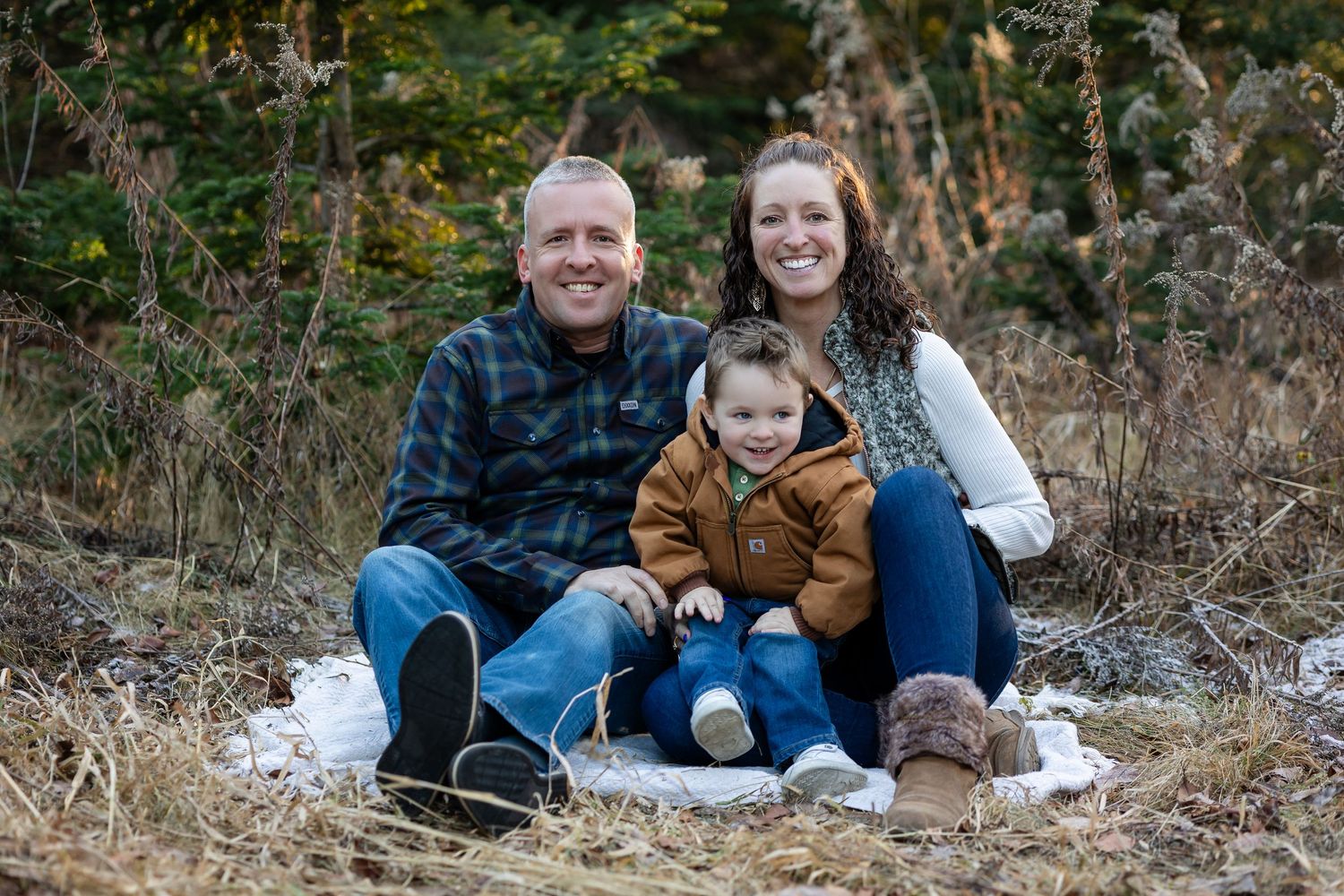 Family group poses together on snowy ground during winter photo session.